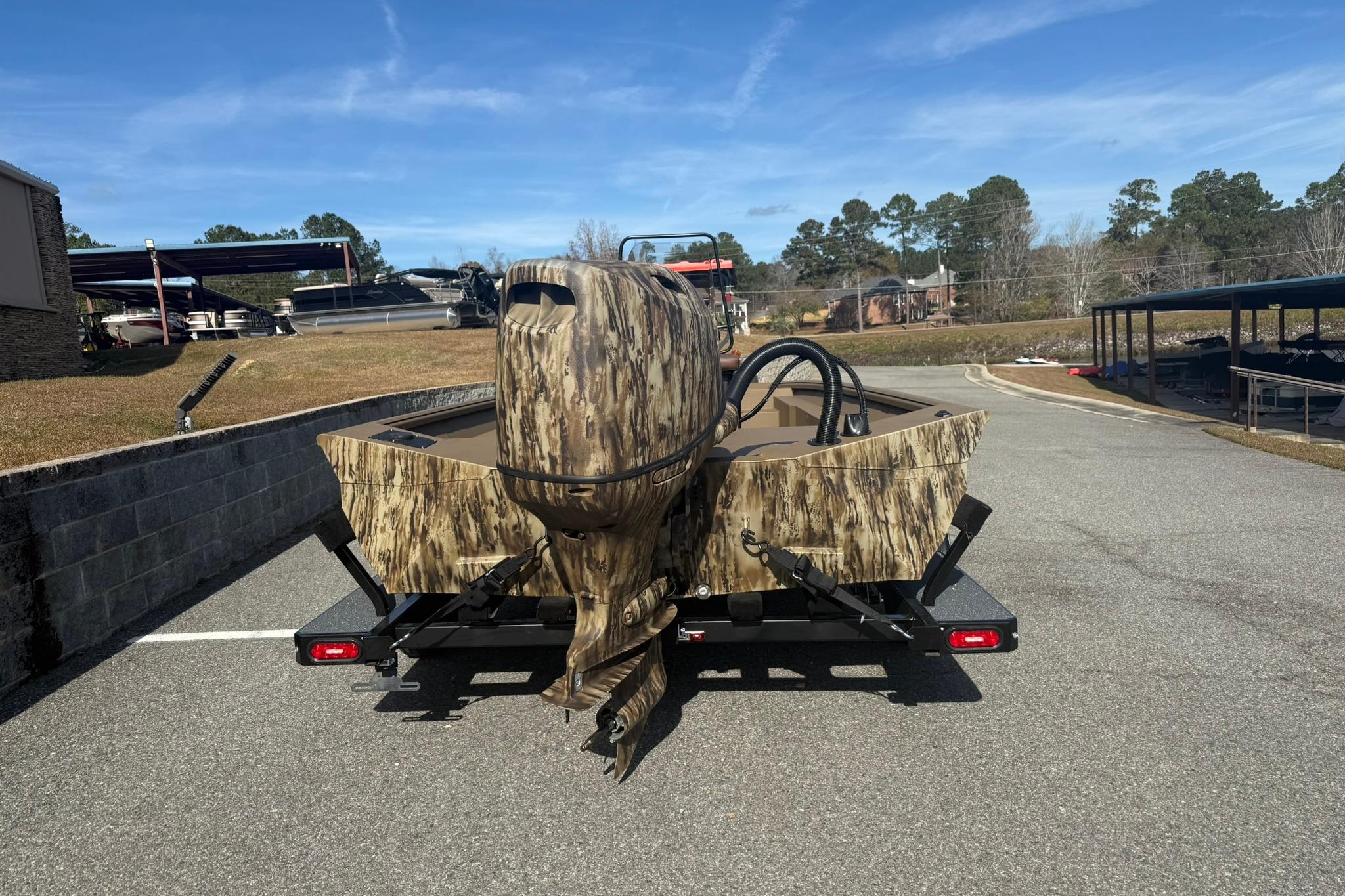2026 Excel 206 Stalker CC boat with camouflage design on a trailer in a parking area.