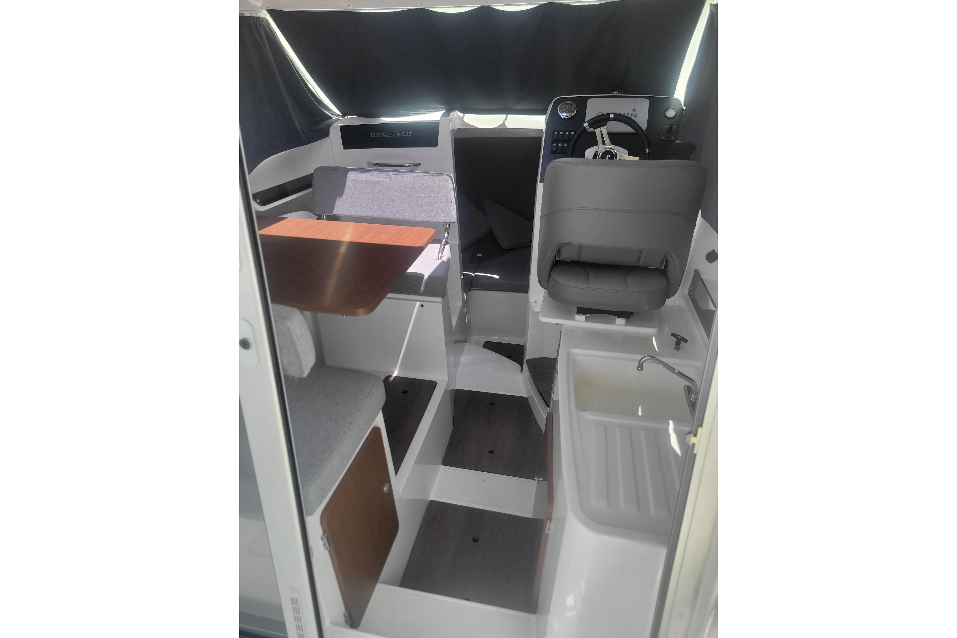 Interior of 2019 Beneteau Antares 23 boat, featuring helm, seating, and compact kitchenette.