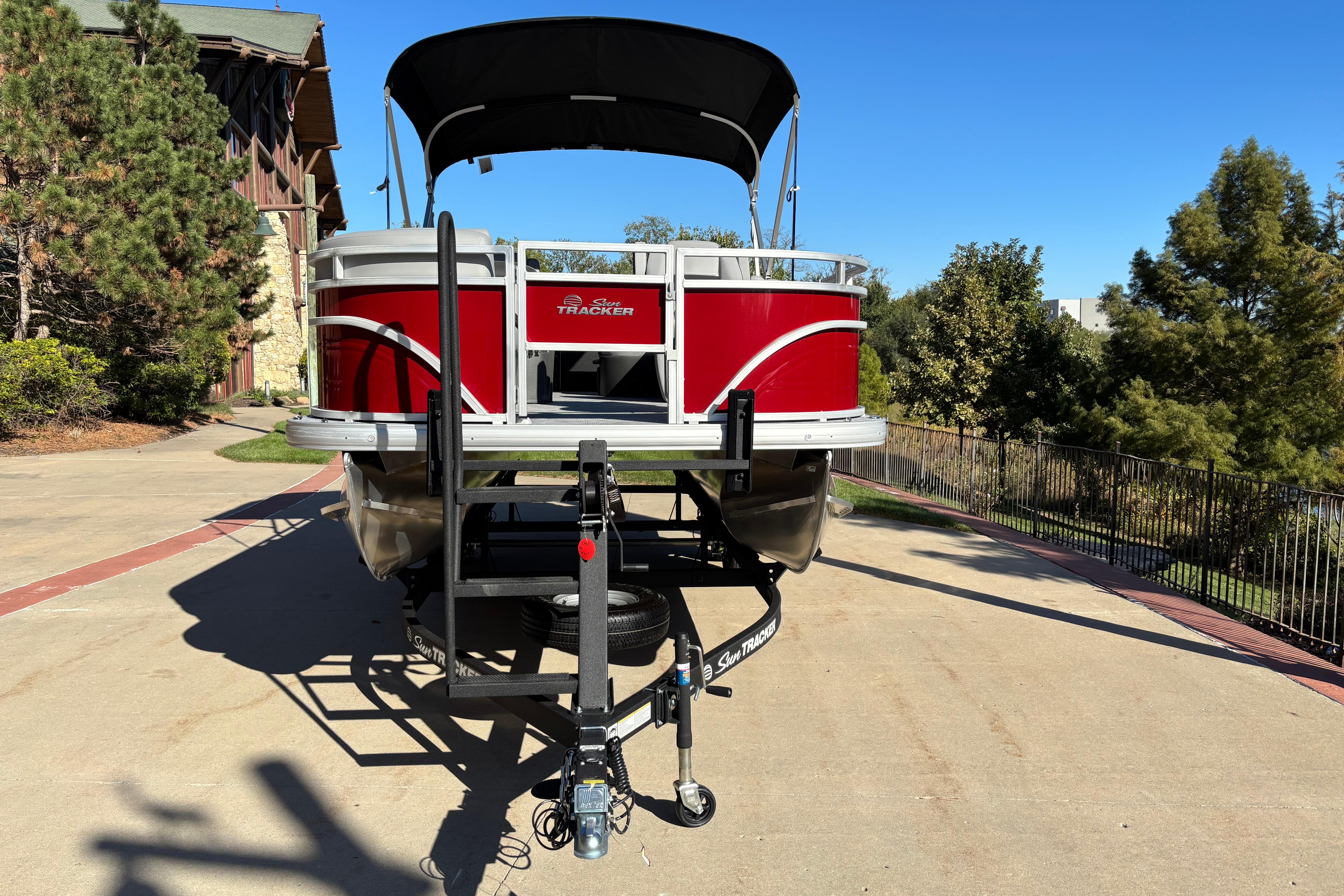 2026 Sun Tracker SportFish 20 DLX pontoon boat on trailer, parked outdoors.