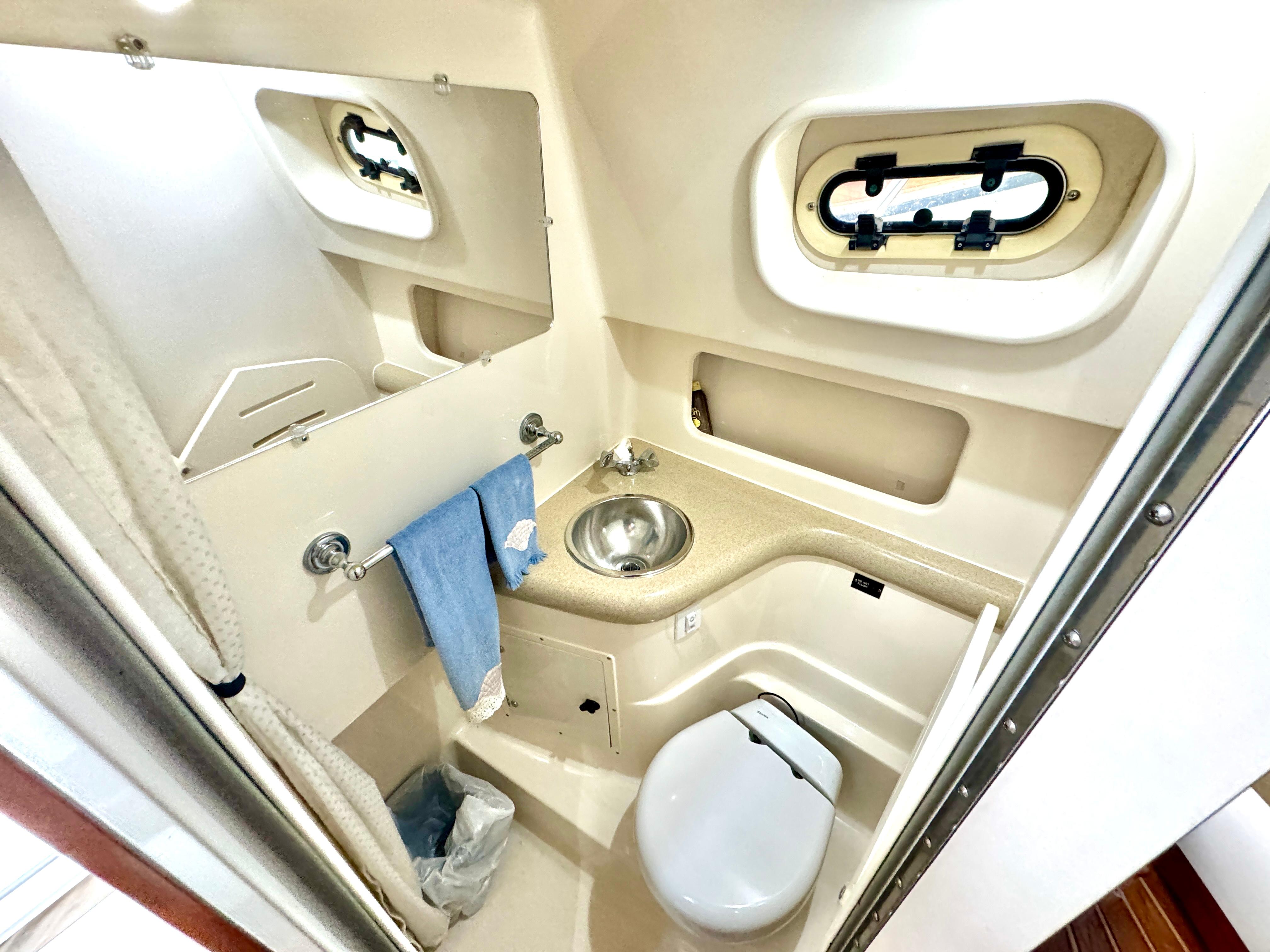 1999 Pursuit 3000 Express boat bathroom with sink, toilet, and porthole window.
