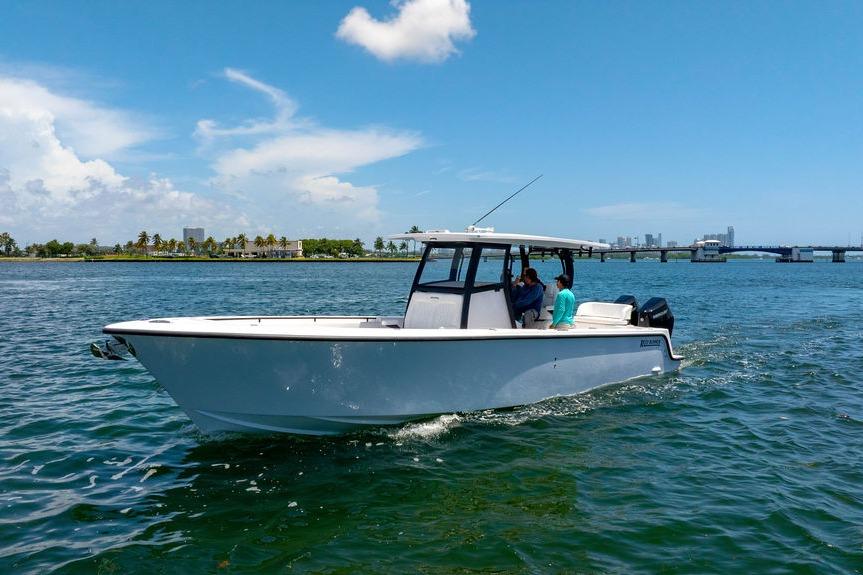 2027 Reef Runner 340 boat cruising on a sunny day near a city skyline.