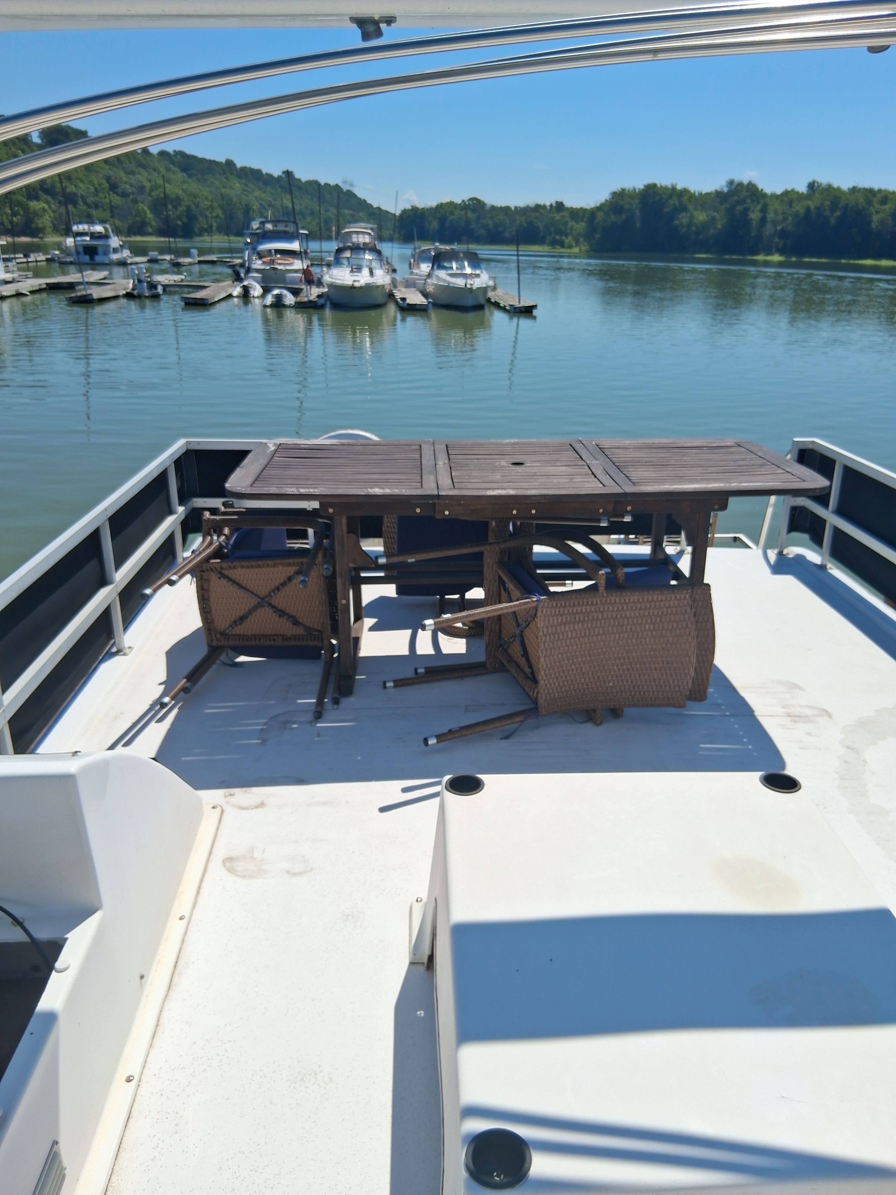 The deck of a 1993 Gibson 370 Sport with overturned chairs and a table, docked in a marina.