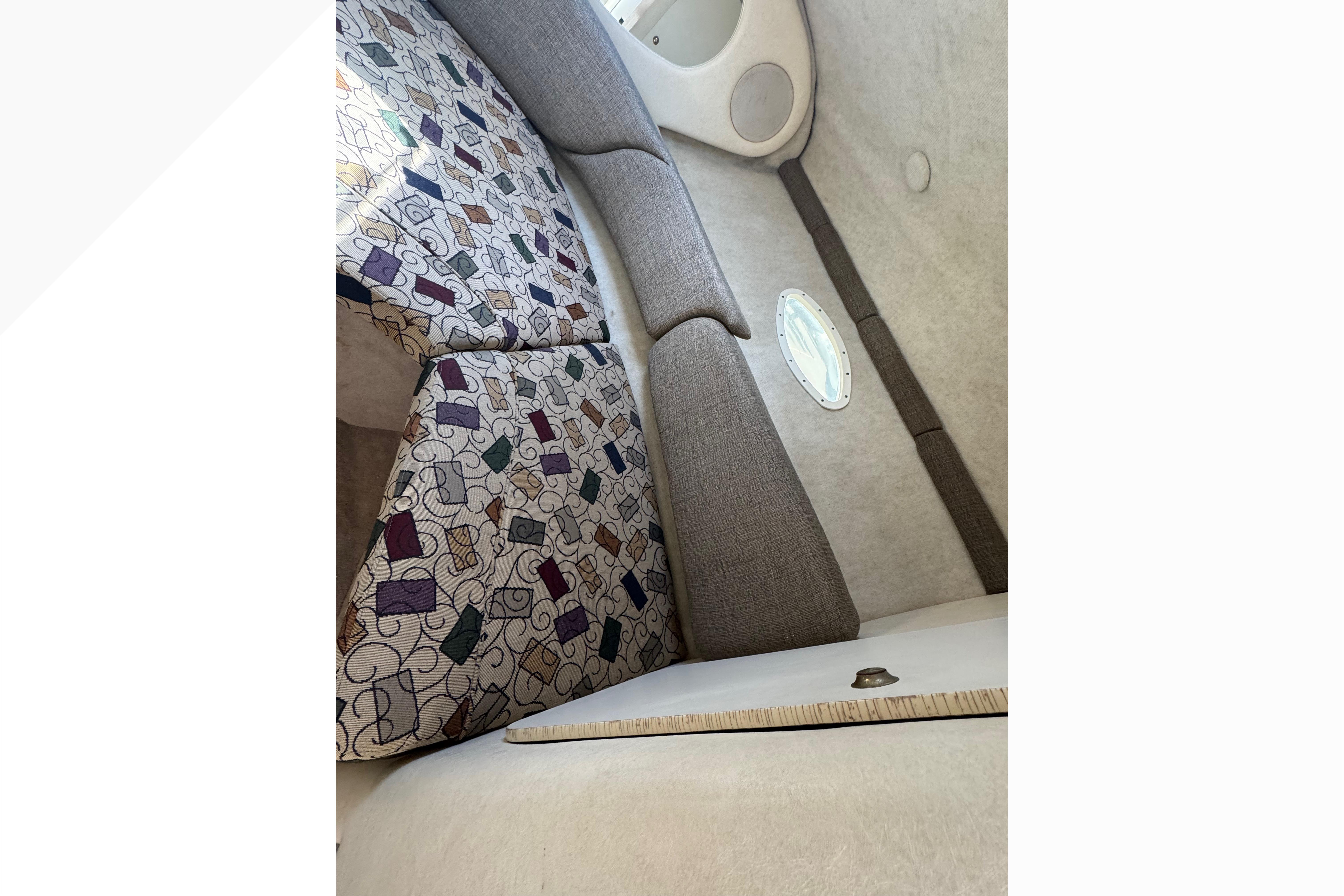 Interior cabin of 2001 Sea Ray 245 Weekender with patterned cushions and small window.