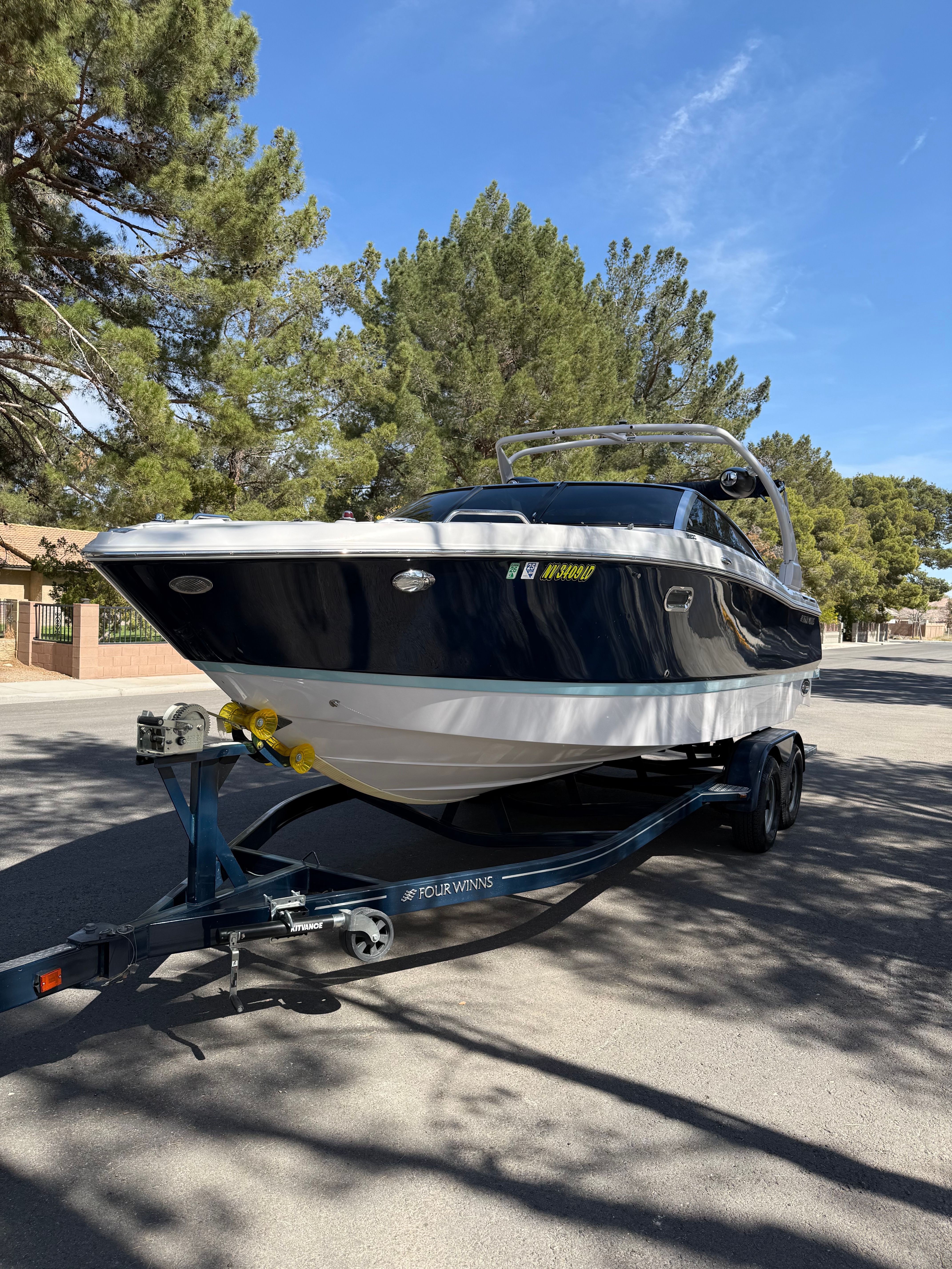 2019 Four Winns H260 boat on trailer, surrounded by trees.