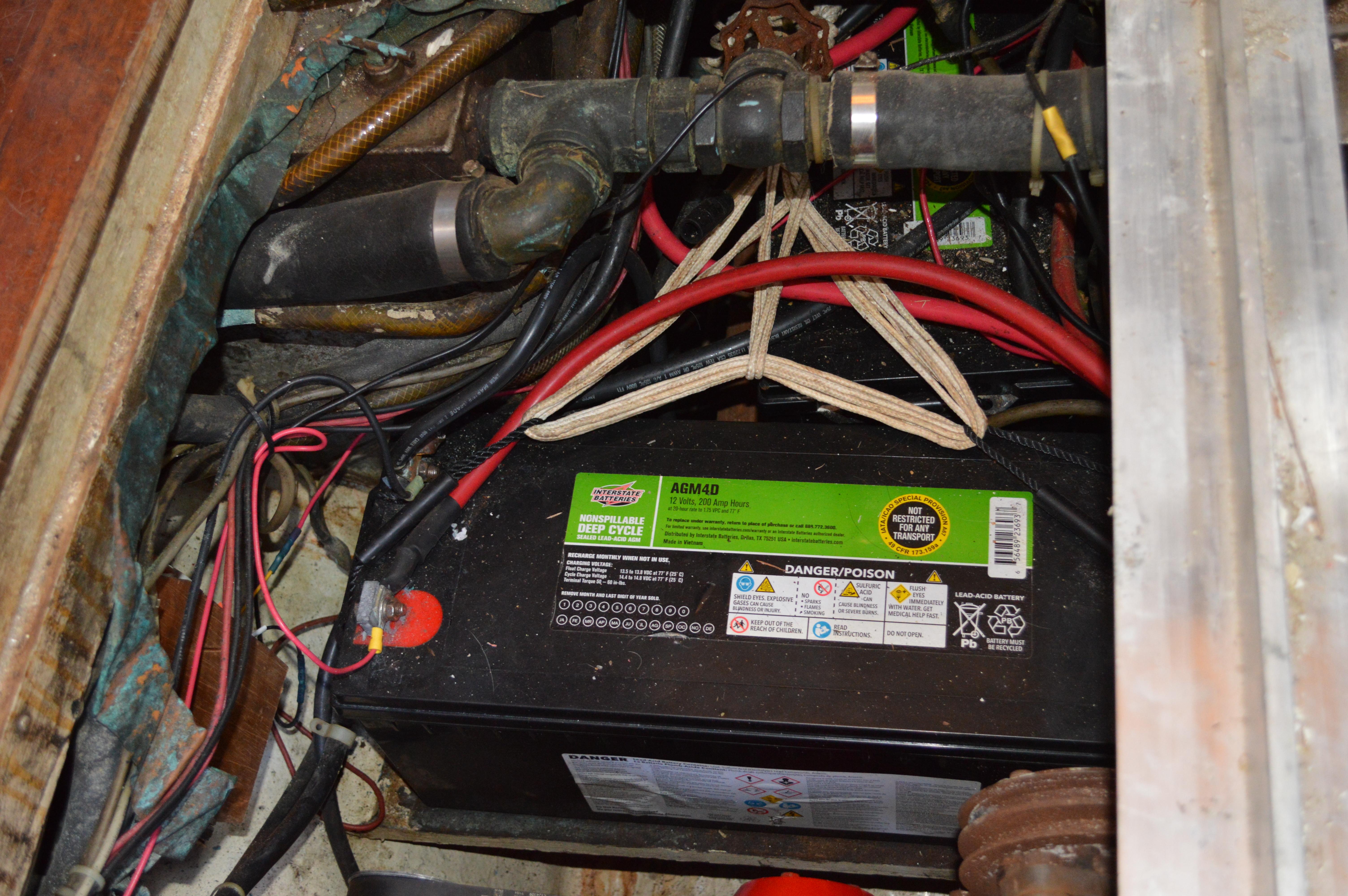 Battery compartment of a 1979 Mason 43 boat with wiring and pipes.