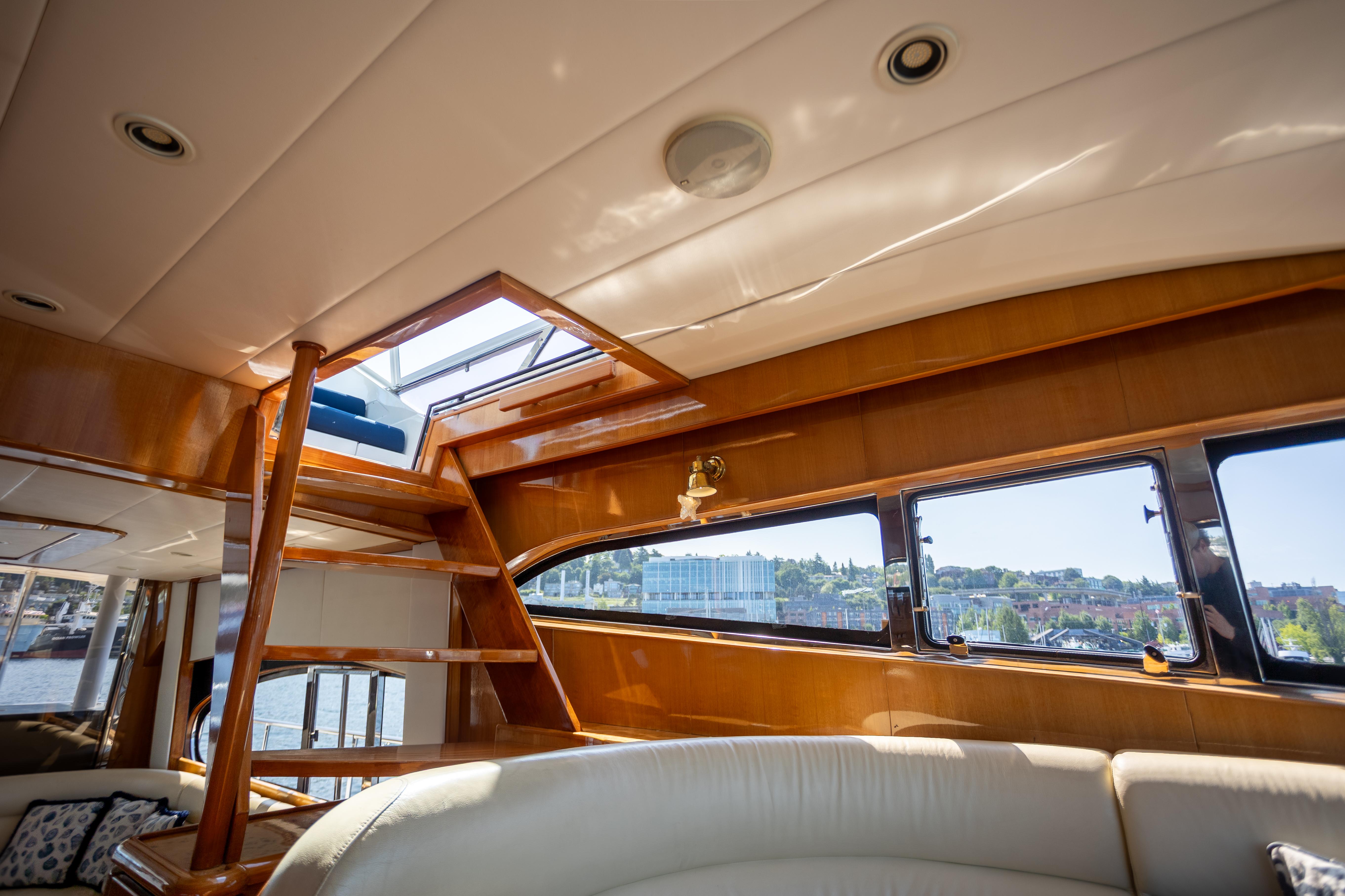 Luxurious interior of 2001 Vitech 72 yacht with wooden staircase and panoramic windows.
