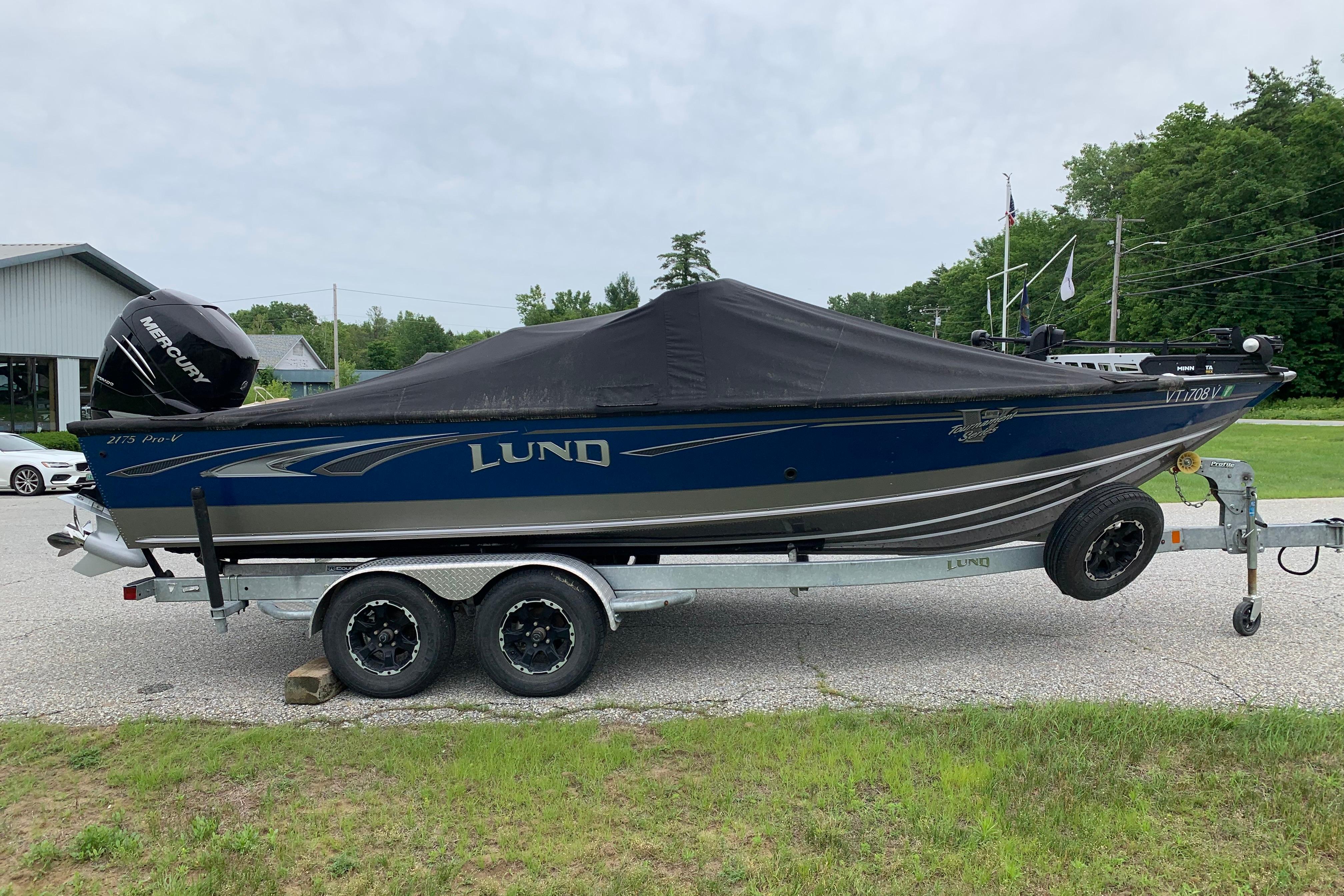 2019 Lund 2175 Pro-V boat on trailer with cover, parked outdoors.