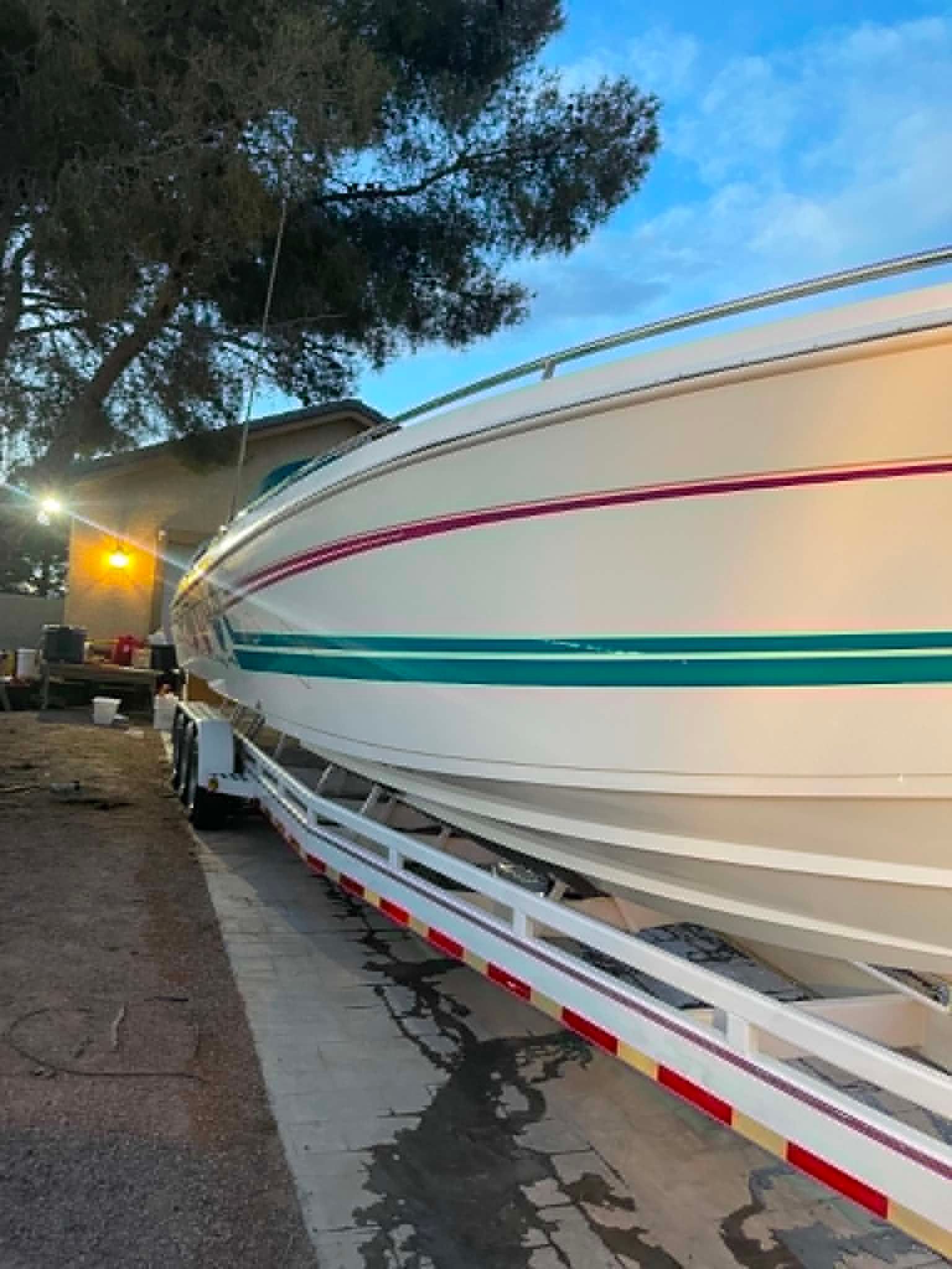A white speedboat with red and green stripes is on a trailer.