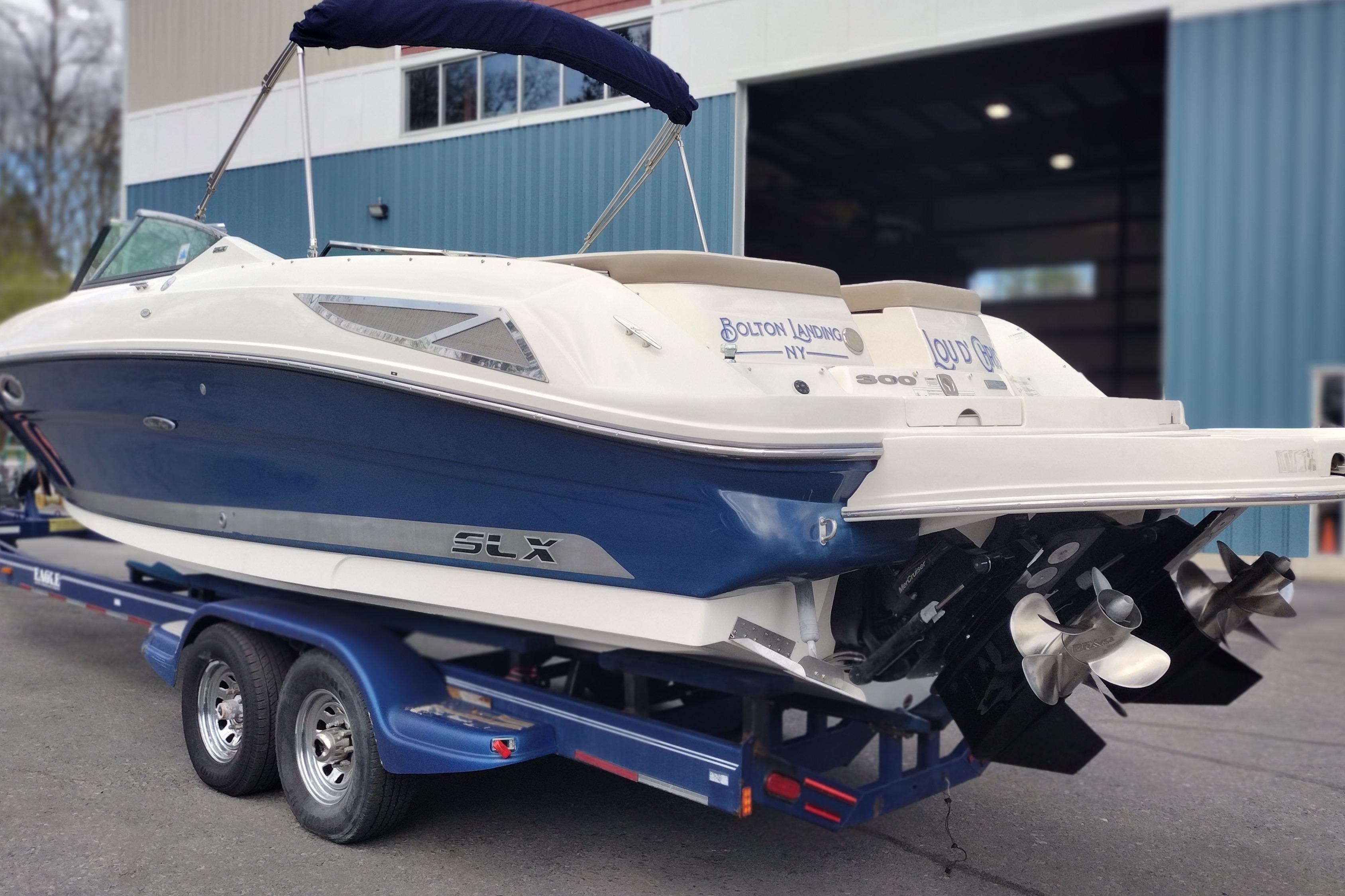 2013 Sea Ray 300 SLX boat on trailer, blue and white exterior, docked near a building.