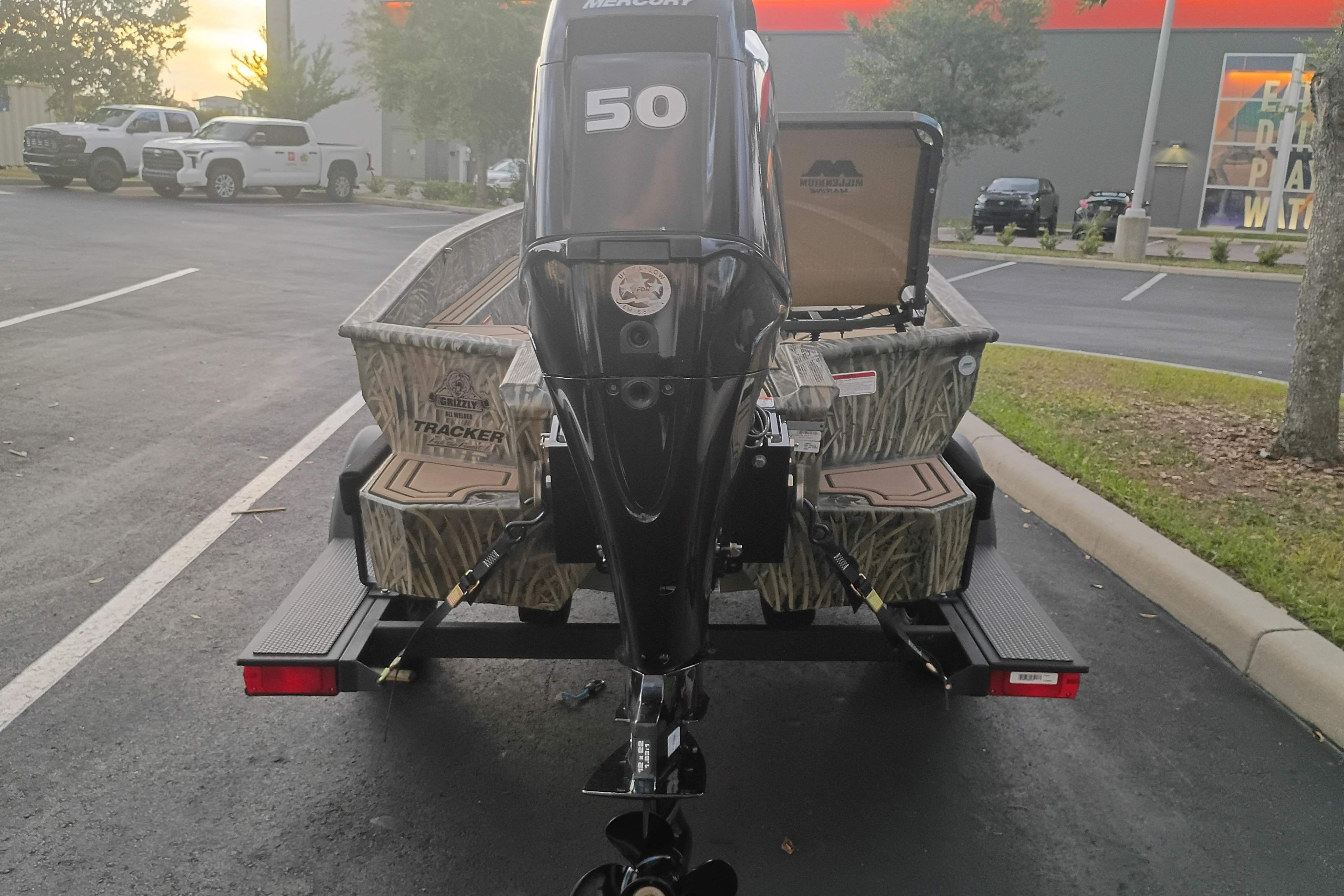 2026 Tracker Grizzly 1650 T Prairie Wings Edition boat with Mercury engine in parking lot.