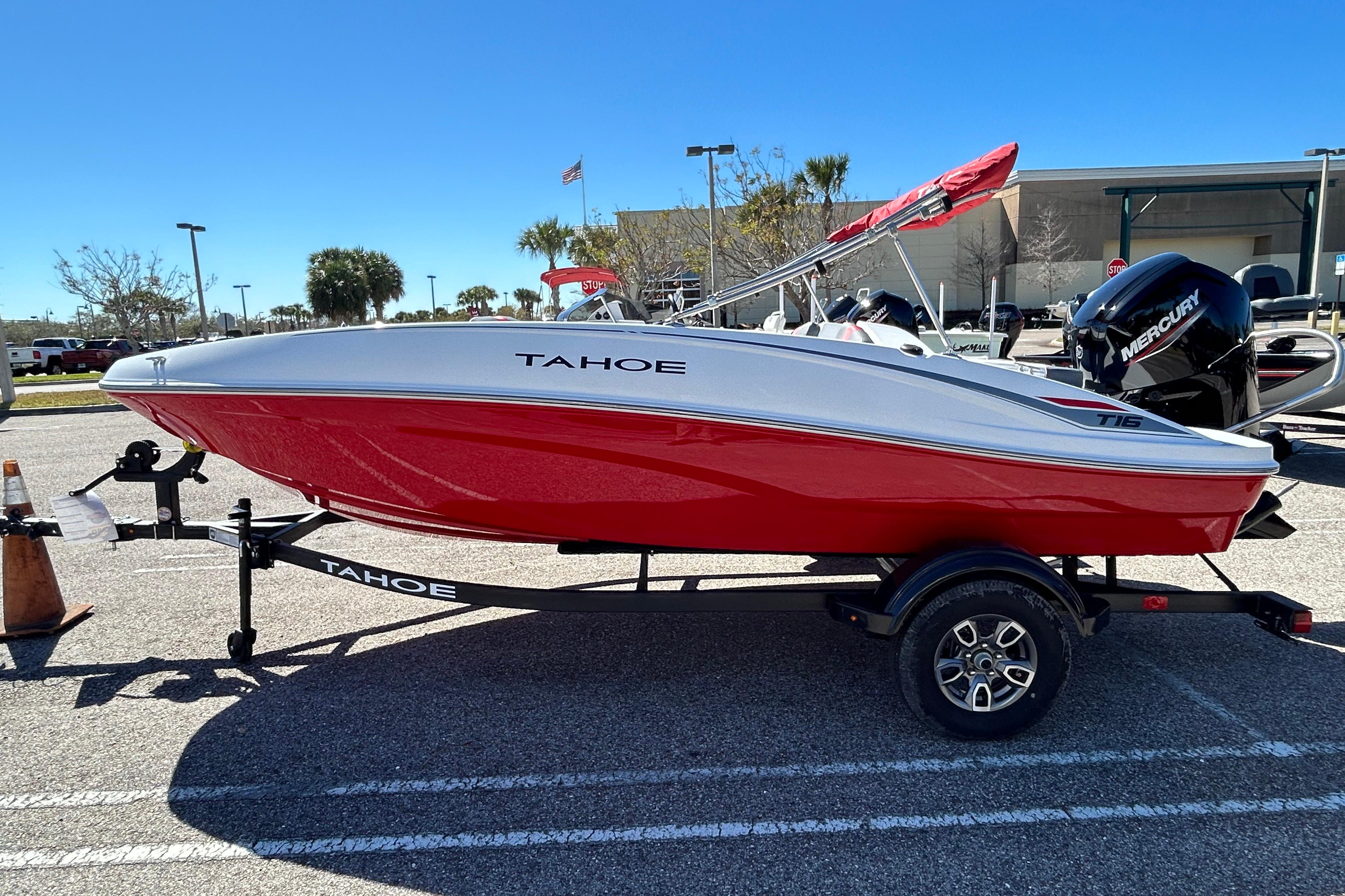 2026 Tahoe T16 boat on trailer, red and white design, parked outdoors.