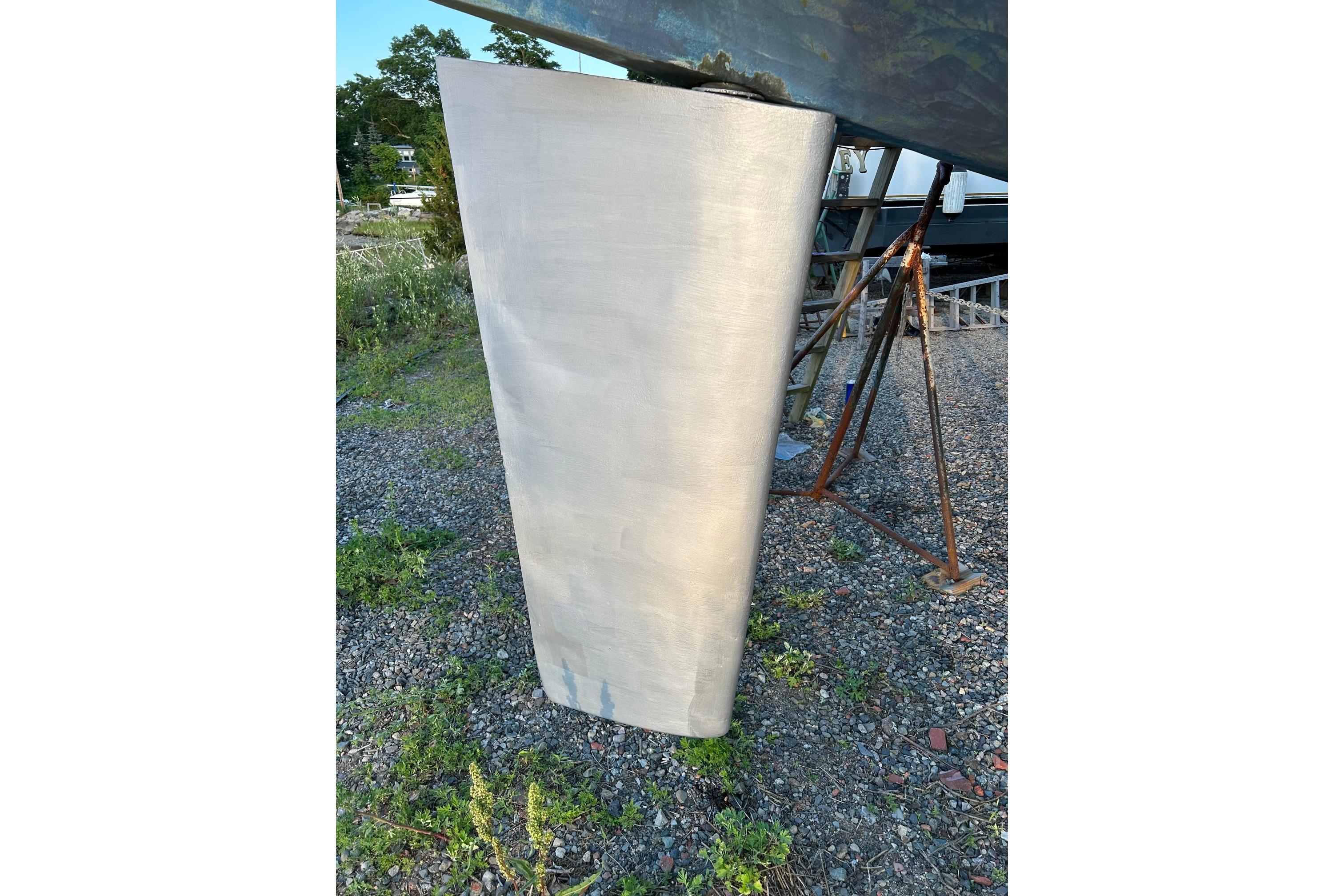 Keel of 1987 Ericson 38-200 sailboat on gravel, supported by stands.