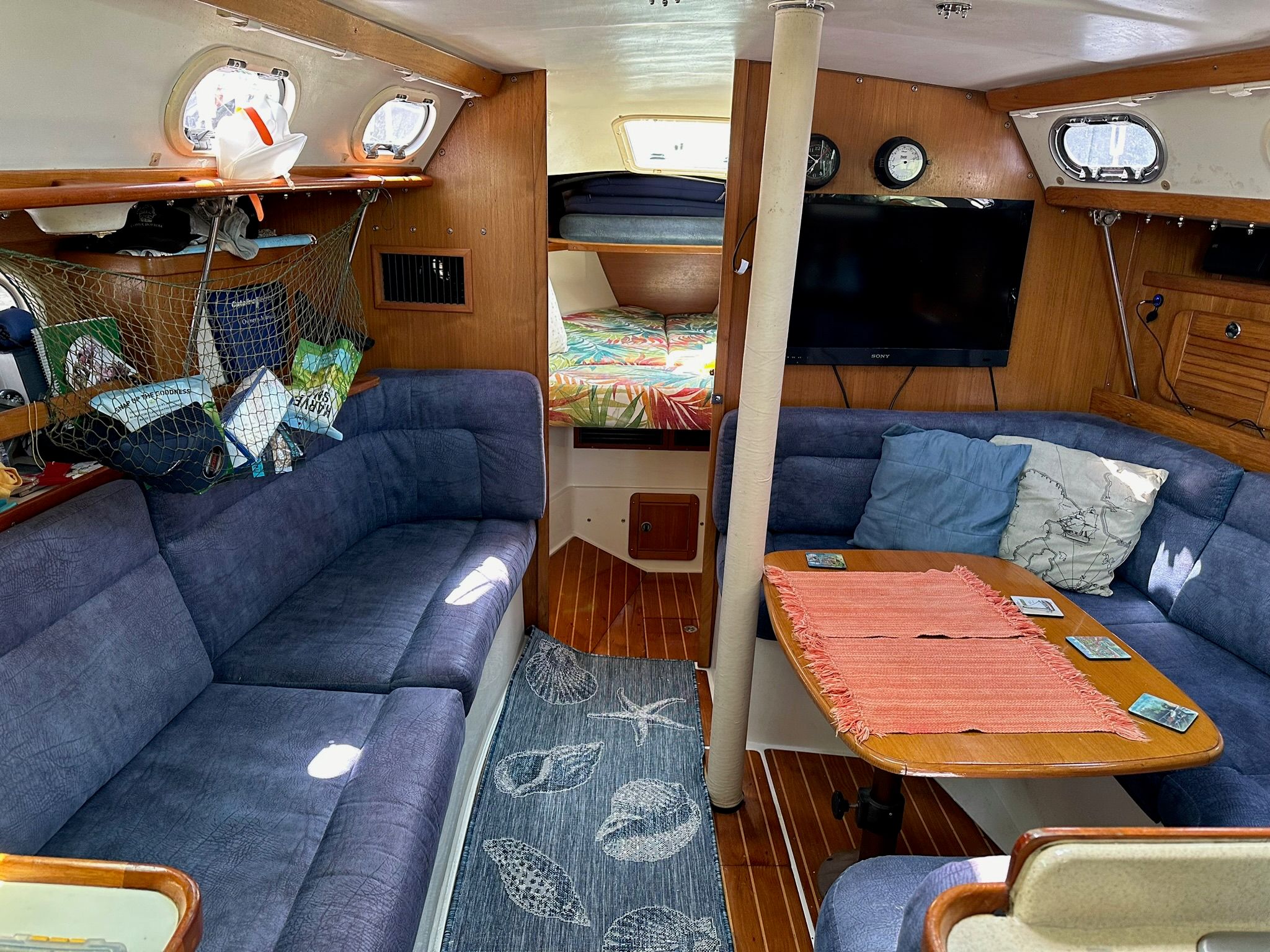 Interior of a Catalina MkII yacht with blue upholstery and wooden furnishings.