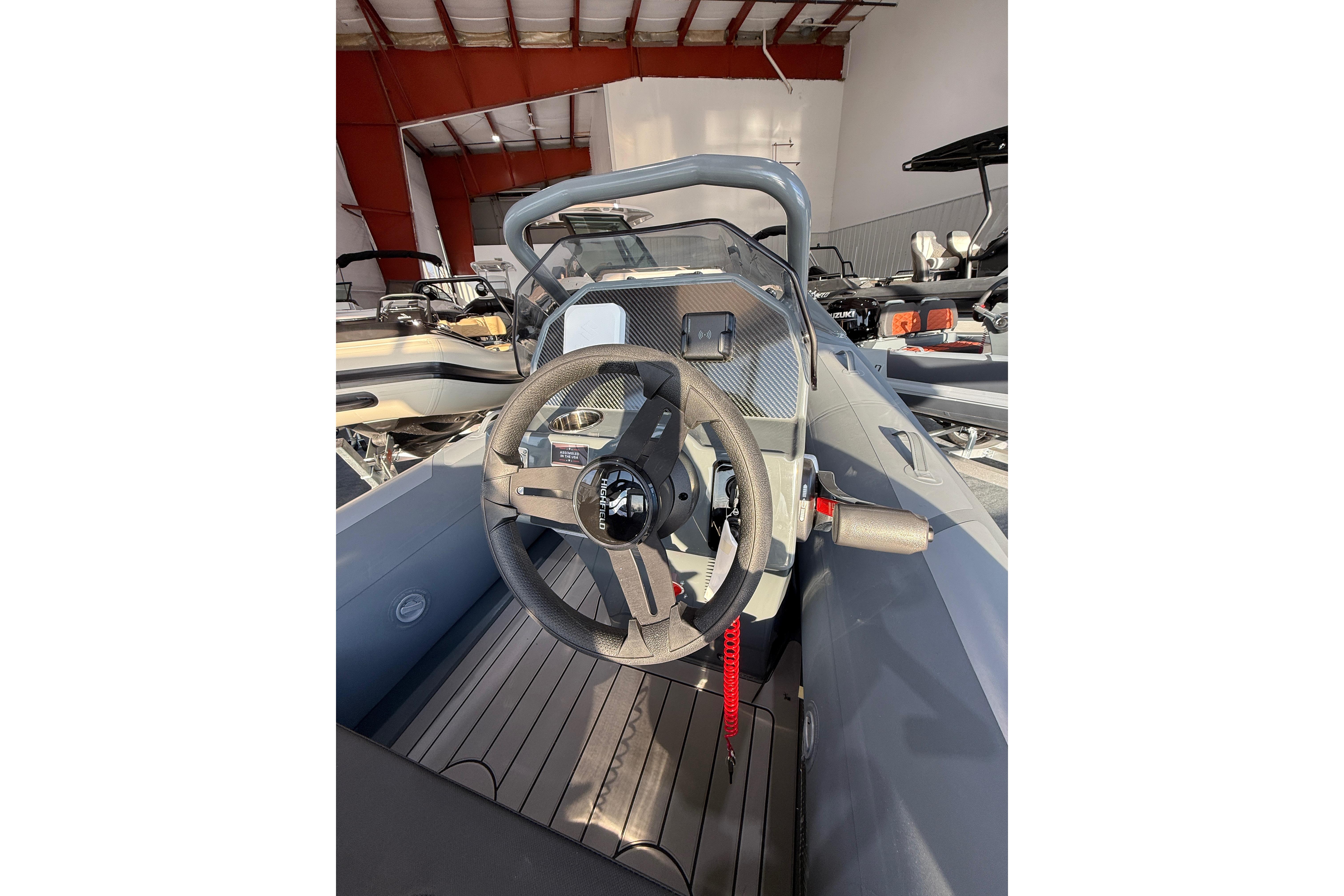 2026 Highfield Sport 390 boat interior with steering wheel and dashboard in a showroom.