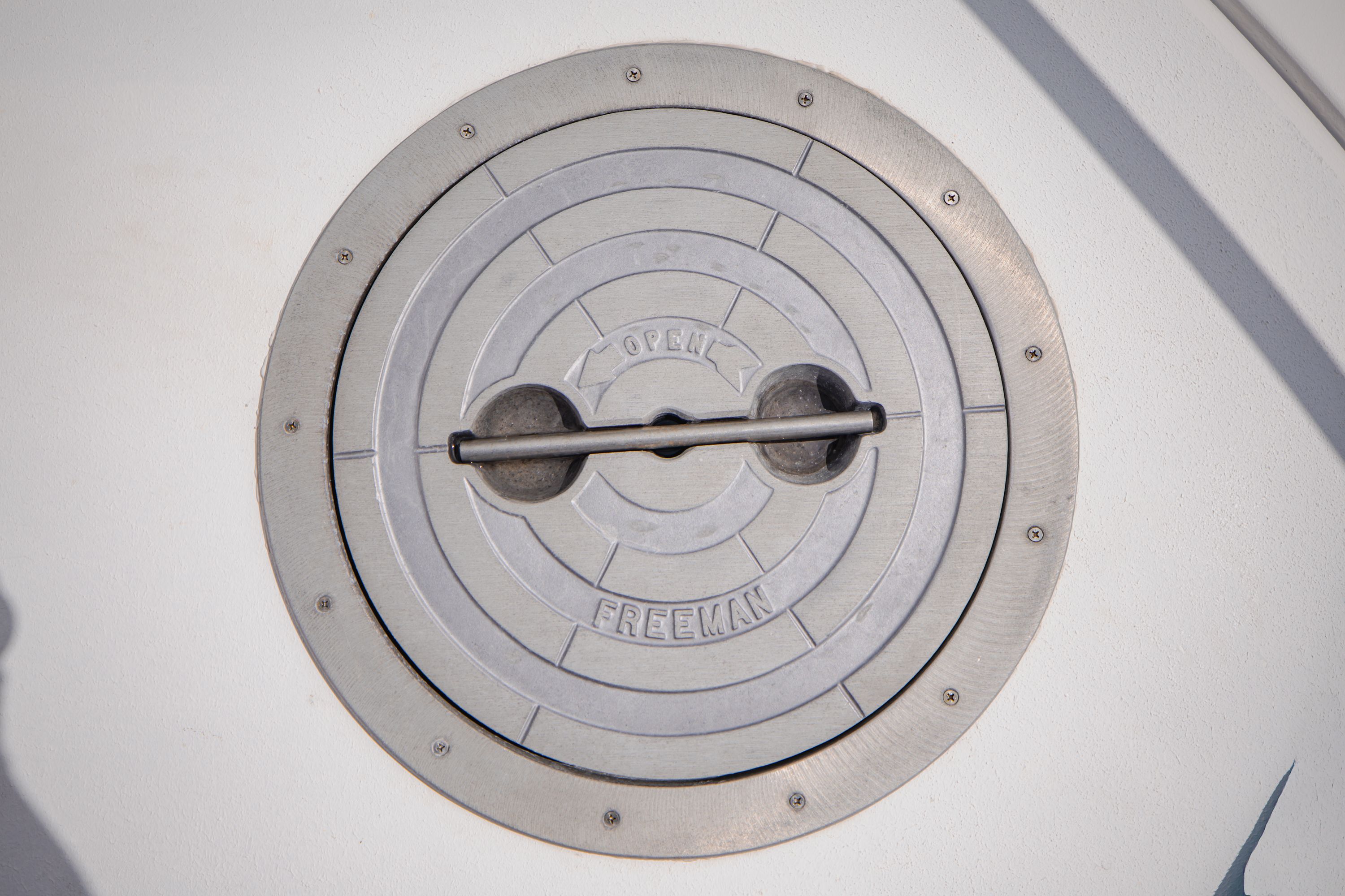 Round metal access hatch on a boat, labeled "OPEN" and "FREEMAN."
