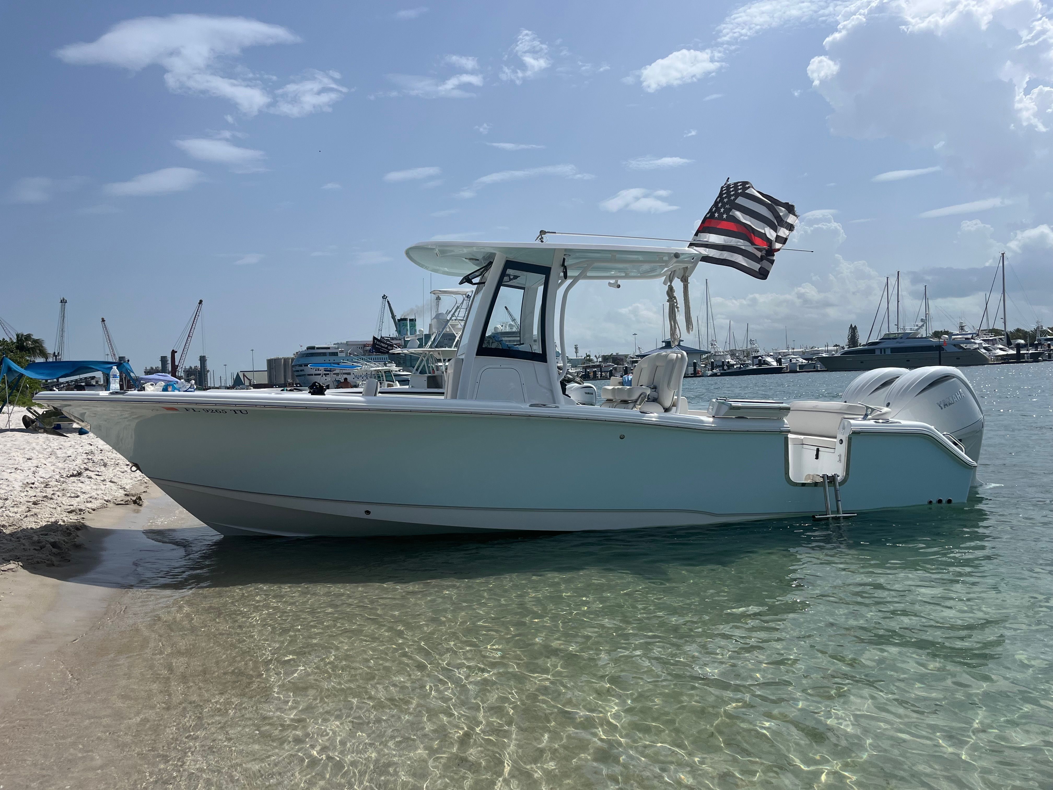 A 2024 Sea Hunt Ultra 265 SE boat is beached. It features a T-top and twin outboard engines.