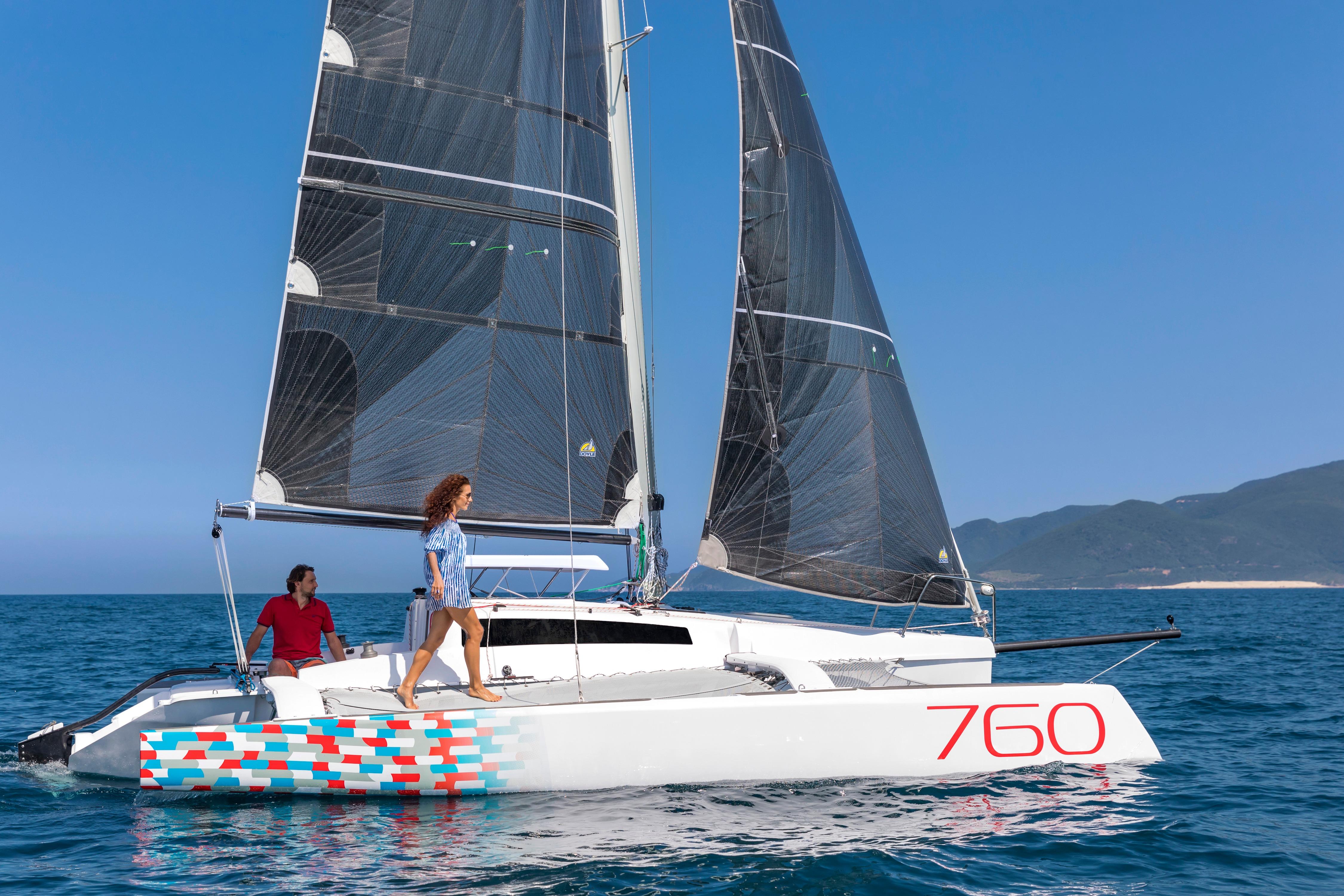 Sleek 2026 Corsair 760 sailboat gliding on blue ocean with two people onboard.