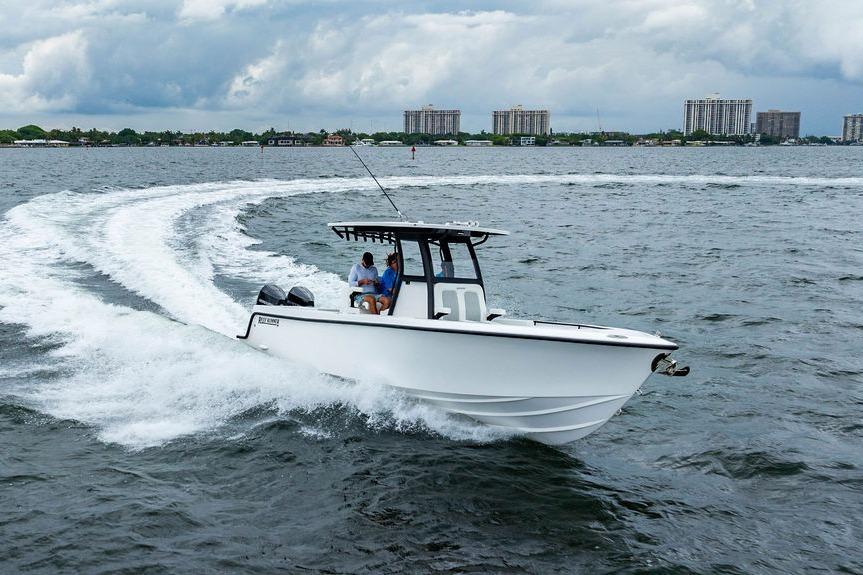2027 Reef Runner 280 boat cruising on a choppy sea with city skyline in background.