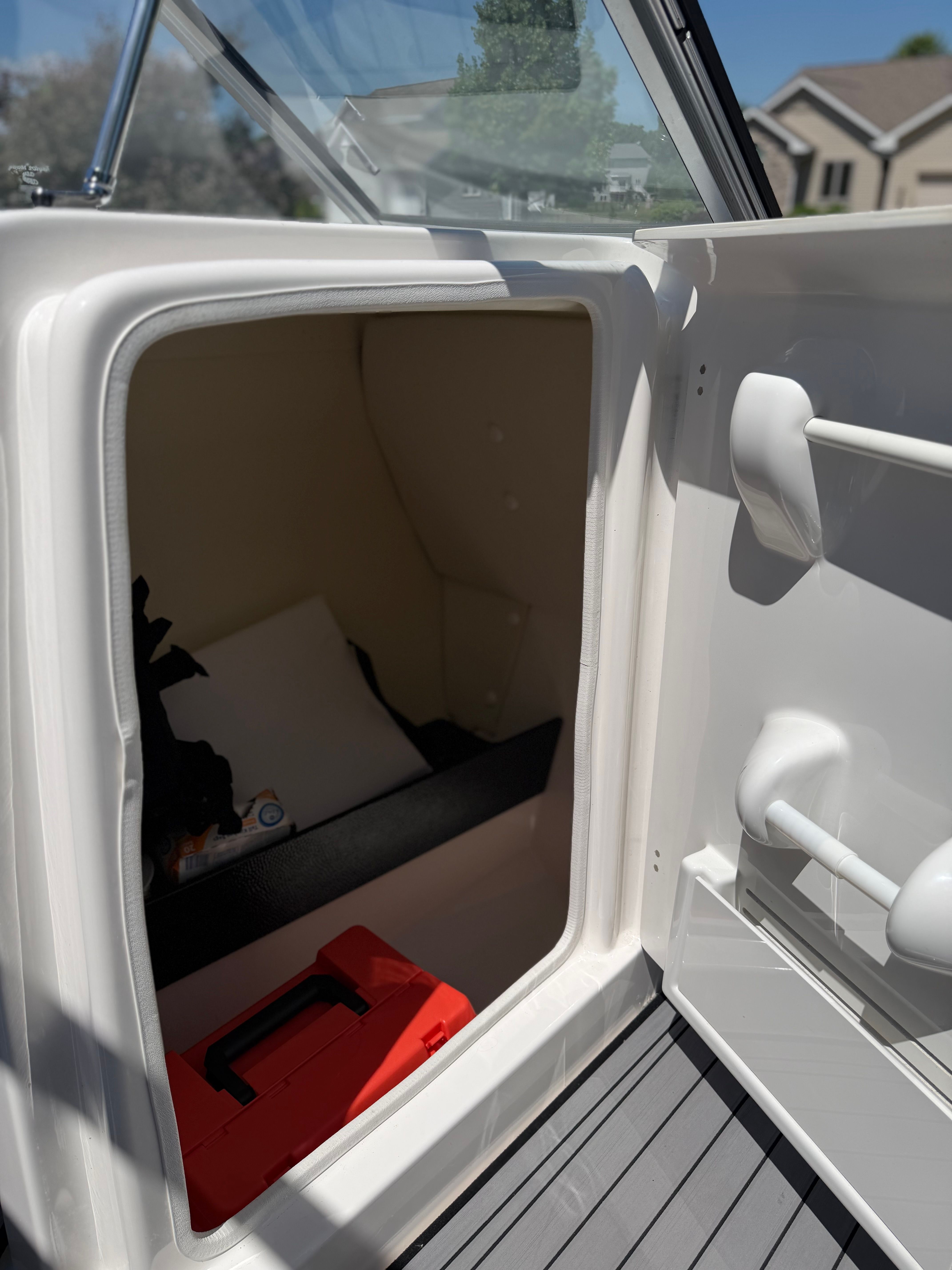 A storage compartment on a boat with a red toolbox and other items.