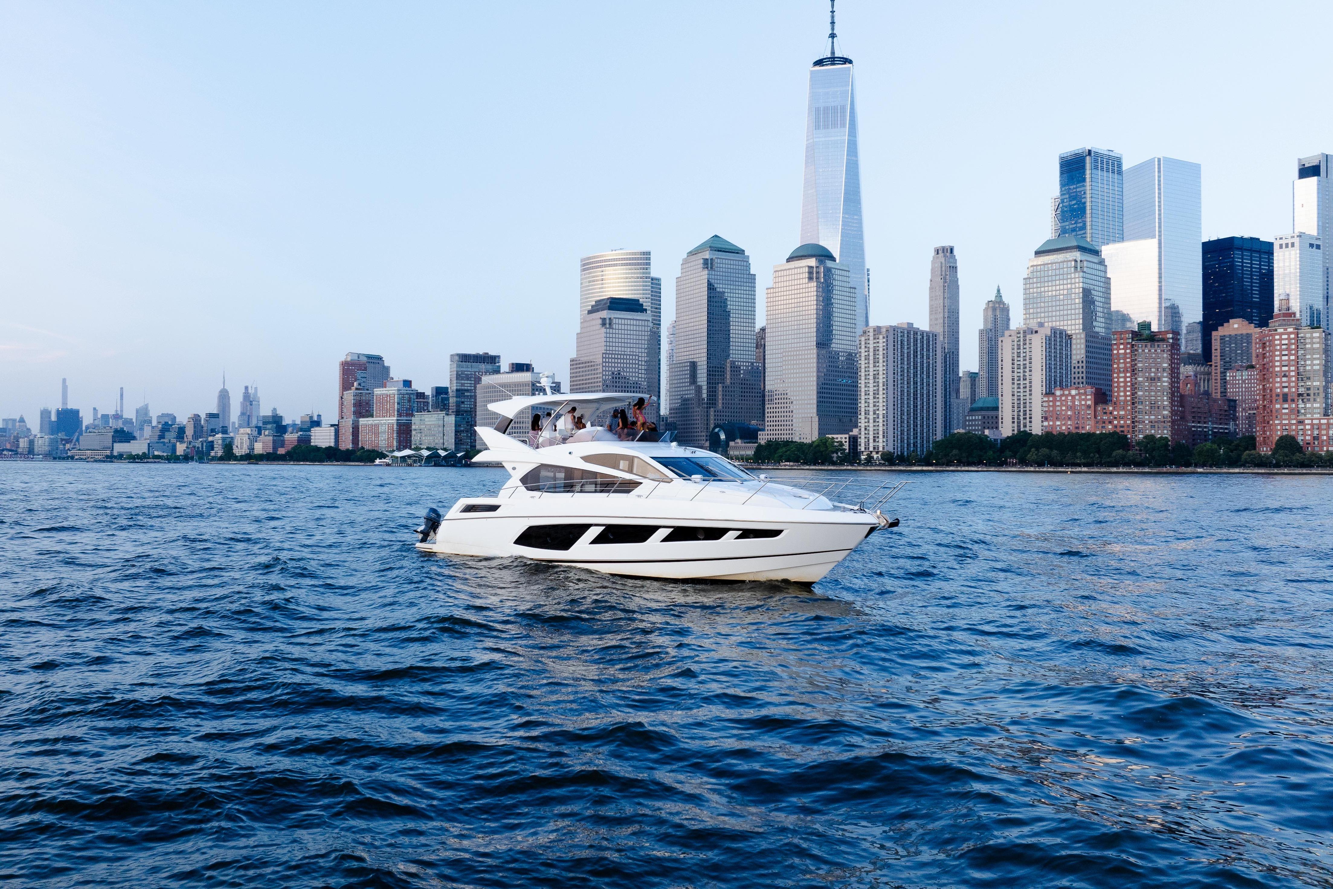 2016 Sunseeker Manhattan 65 yacht cruising near a city skyline on a clear day.