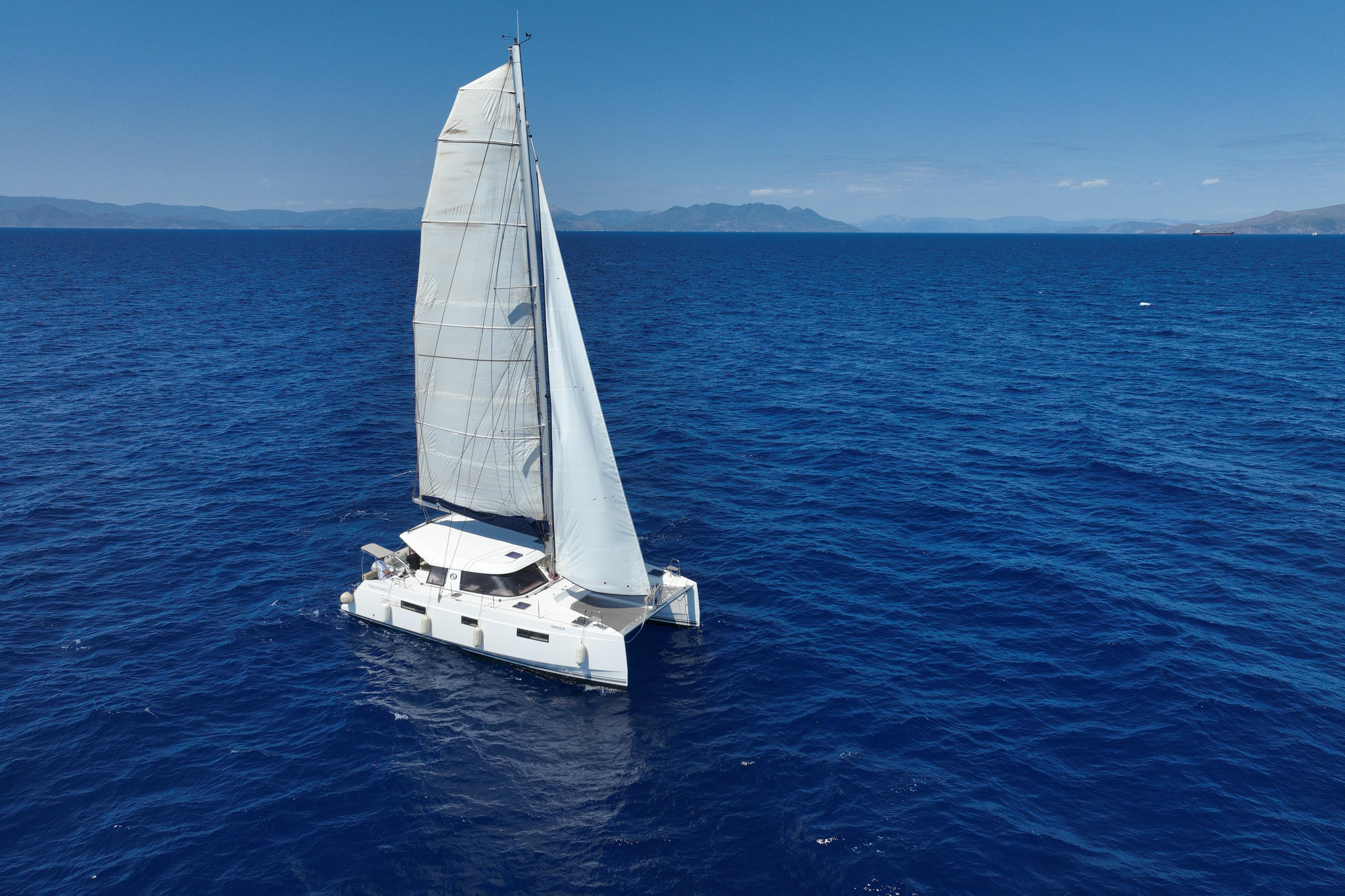 Sailing catamaran Nautitech 40 Open 2016 on open sea under clear blue sky.
