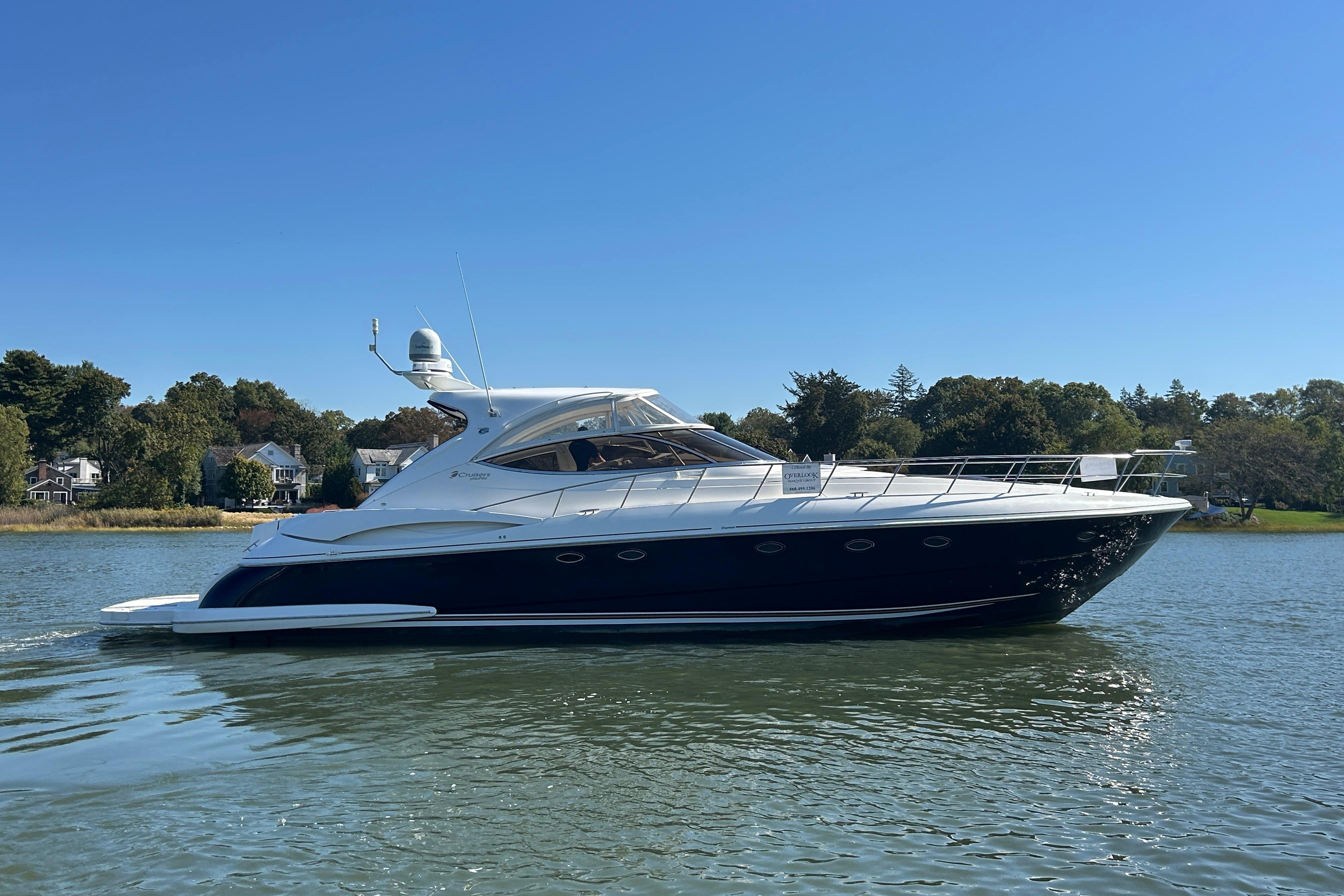 2003 Cruisers Yachts 540 Express on calm water, surrounded by trees and houses.