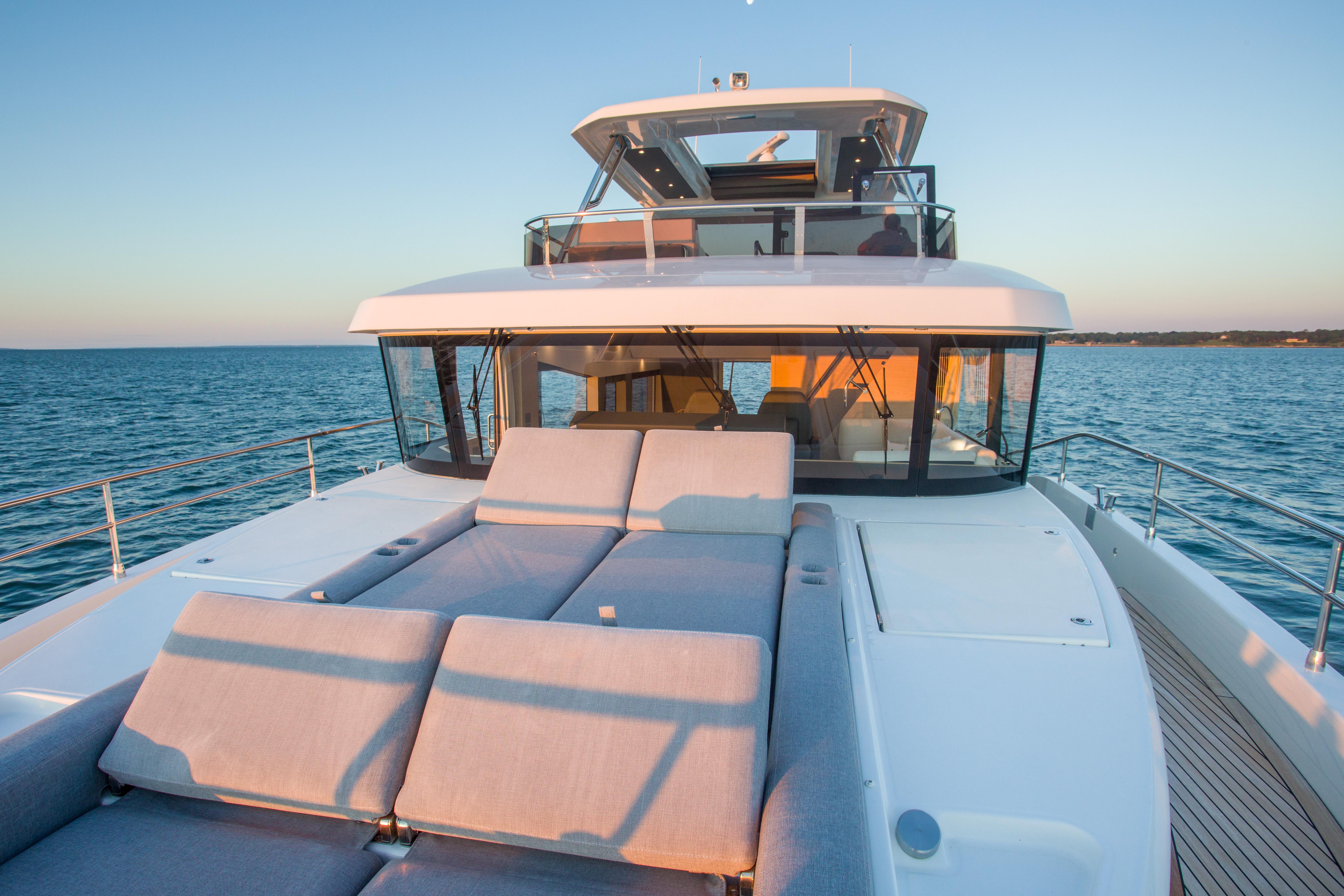 2025 Beneteau Grand Trawler 62 yacht with sun loungers on deck, ocean view.