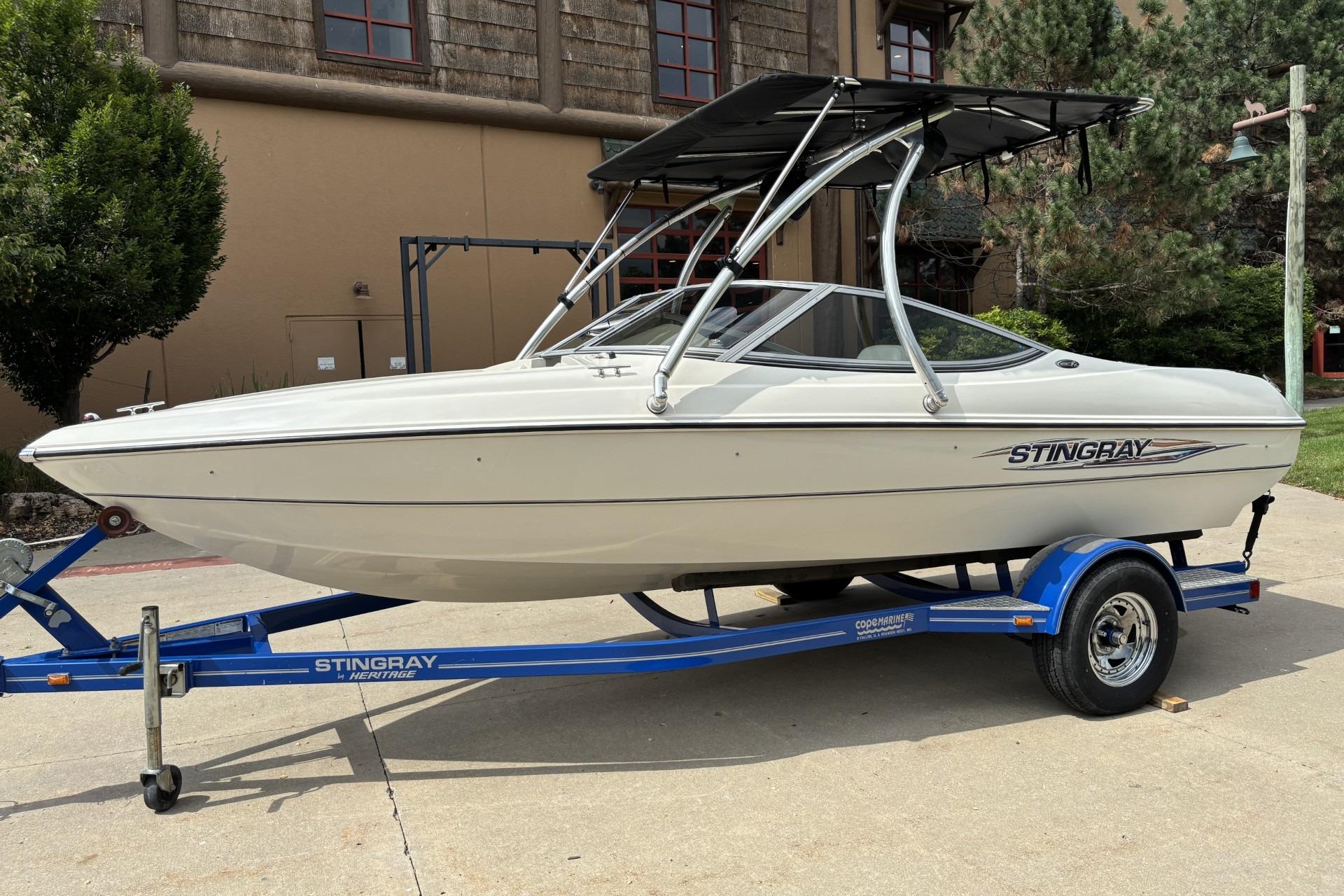 2007 Stingray 180 RX boat on a blue trailer, parked outdoors.