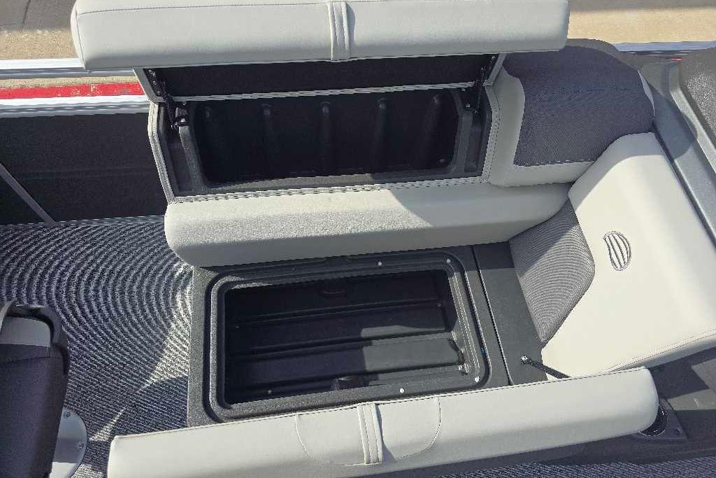 2026 Sun Tracker Fishin' Barge 20 DLX storage compartment with open seat and textured flooring.