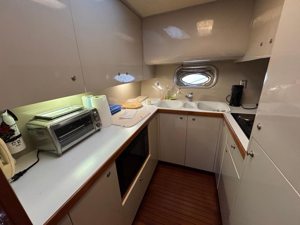 1989 Birchwood 62 Cockpit Motor Yacht kitchen with modern appliances and wooden flooring.