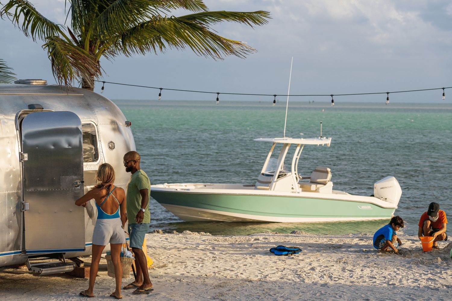 A boat is anchored in turquoise water as people relax on the beach.