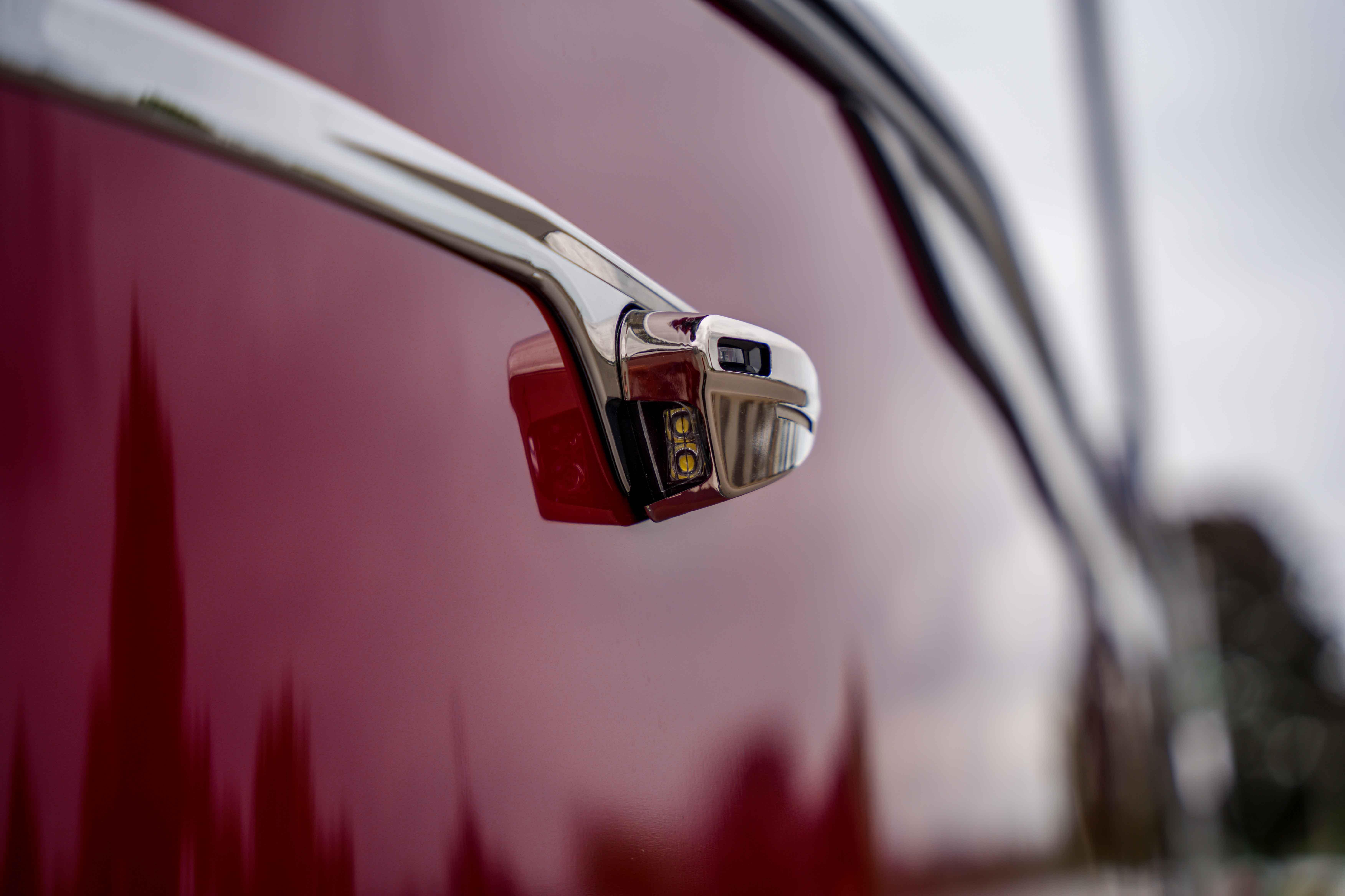 Close-up of 2026 Harris Sunliner 230 side mirror on a glossy red surface.