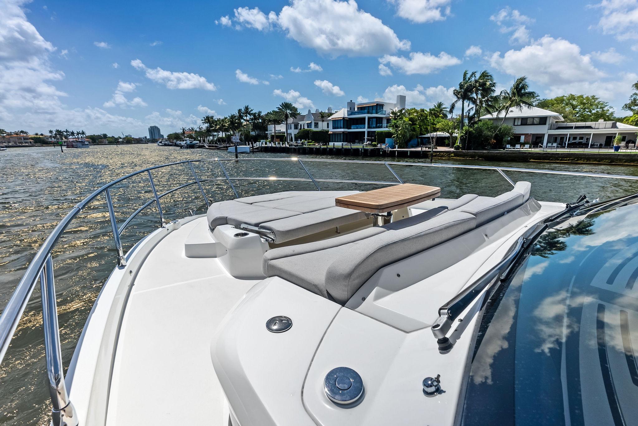 2023 Absolute 52 FLY yacht cruising on a sunny day with waterfront homes in the background.