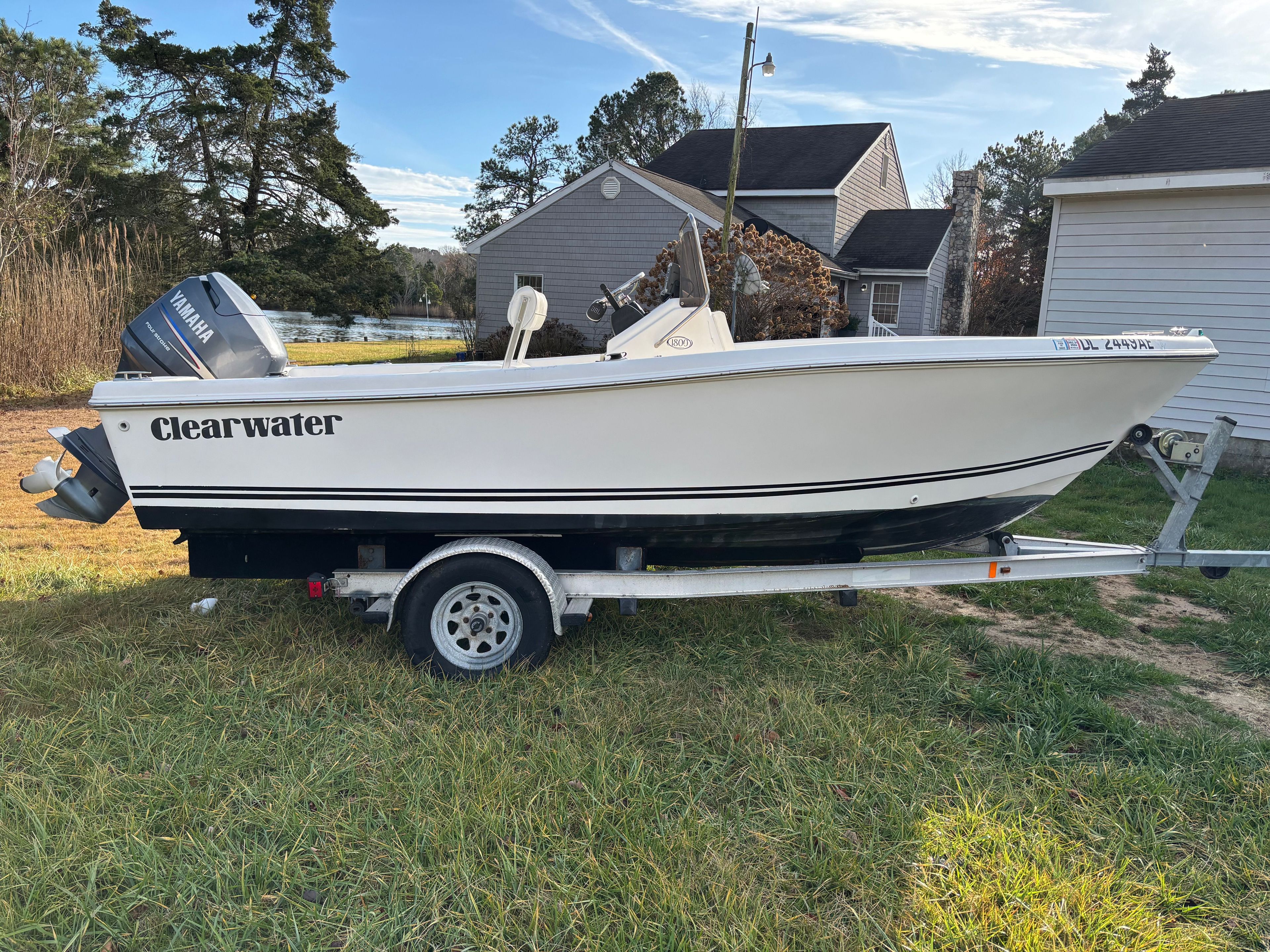 A Clearwater boat on a trailer, next to a house, with trees in the background.