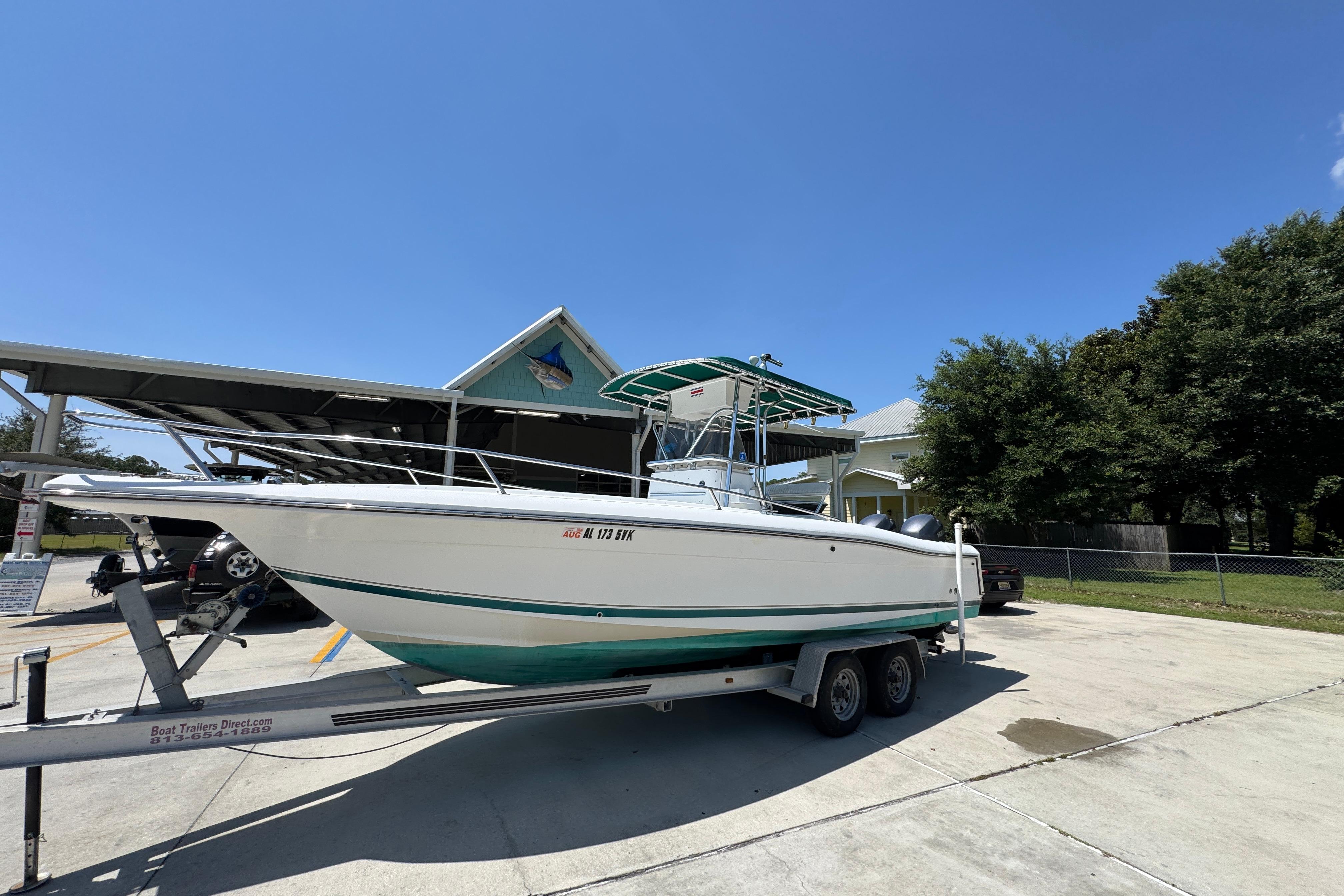 2000 Stamas 250 Tarpon boat on trailer, parked outdoors under clear blue sky.