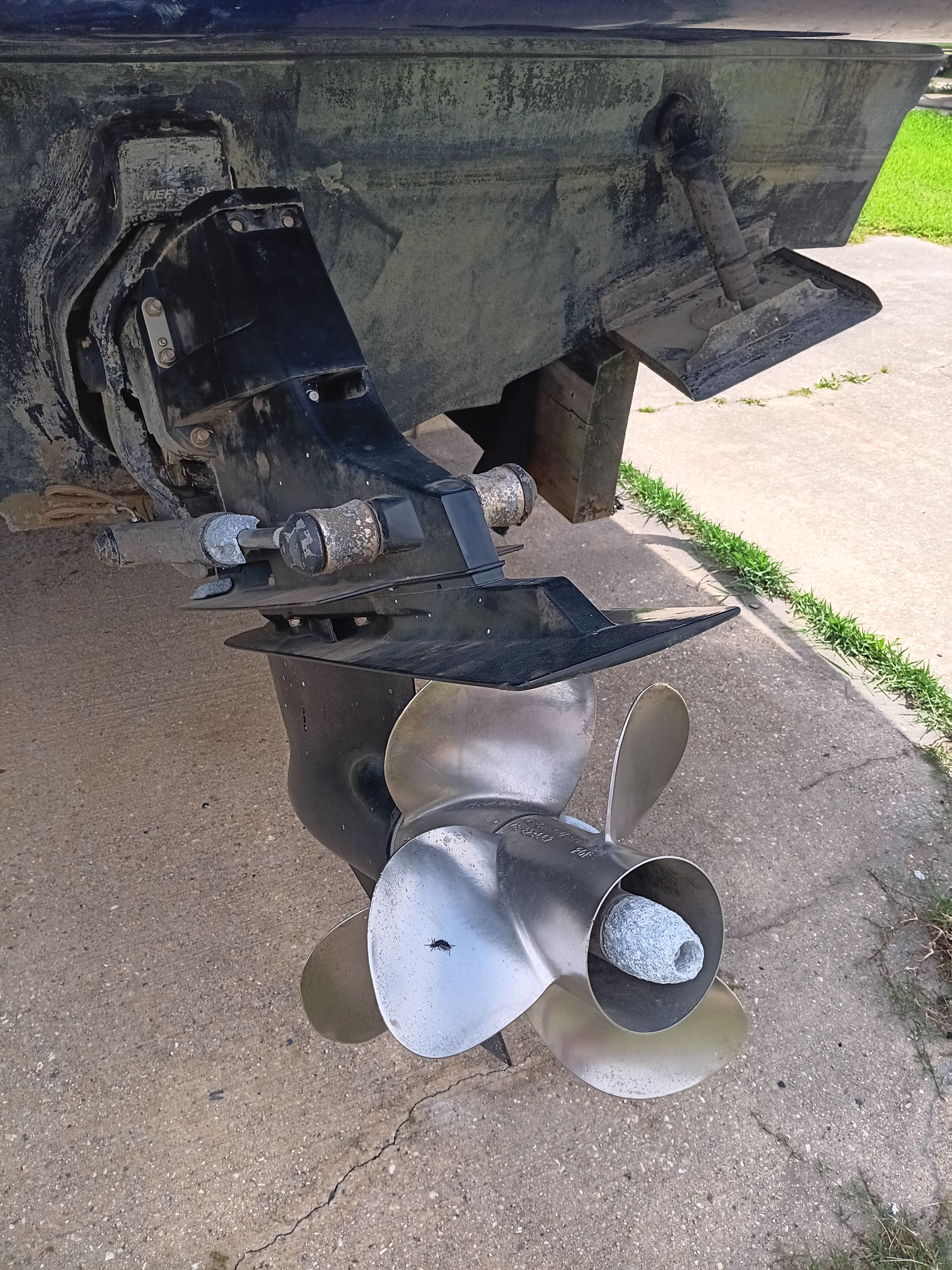 Close-up of a boat propeller and drive system on a concrete surface.