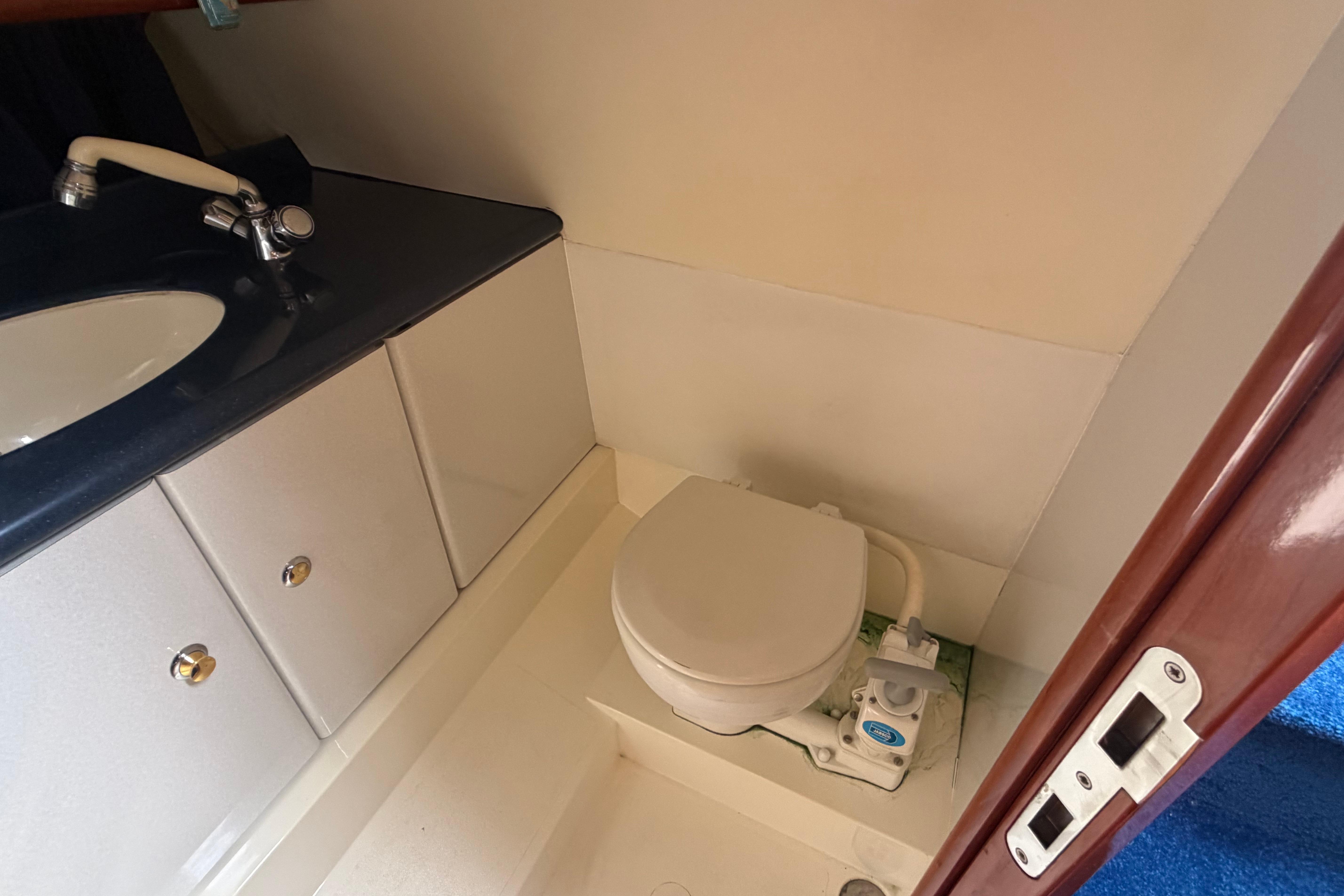 Bathroom interior of 2000 Sunseeker Superhawk 34 yacht, featuring toilet and sink.