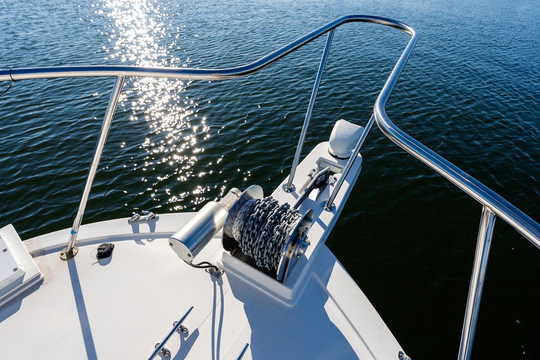 Bow of 2024 Steiger Craft 31 Fisherman with anchor chain, glistening water.