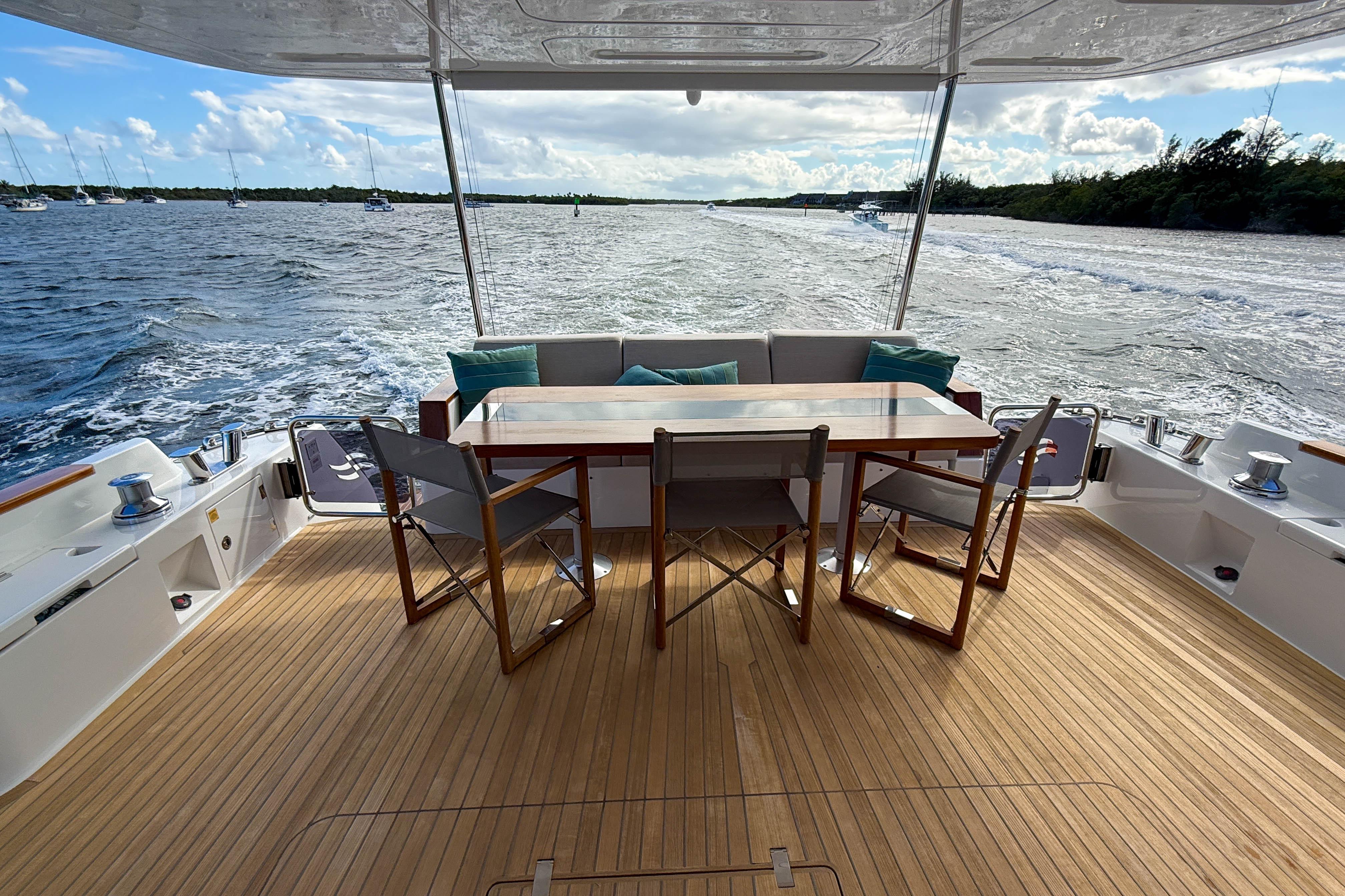 Luxurious 2023 Sirena 68 yacht deck with dining area, overlooking serene ocean waters.