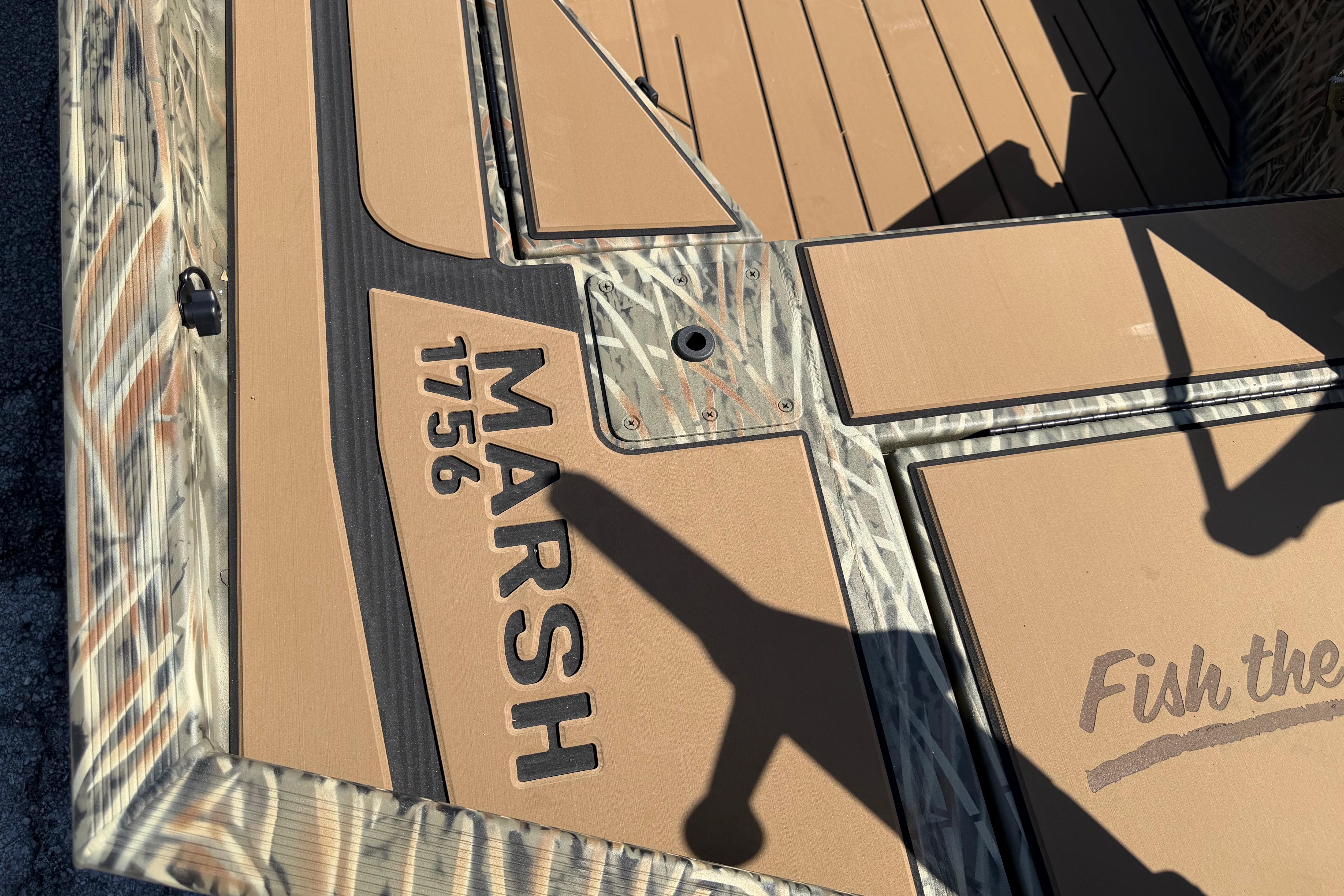 2026 Tracker Grizzly 1756 T Marsh boat deck with camouflage design and "Fish the" text.