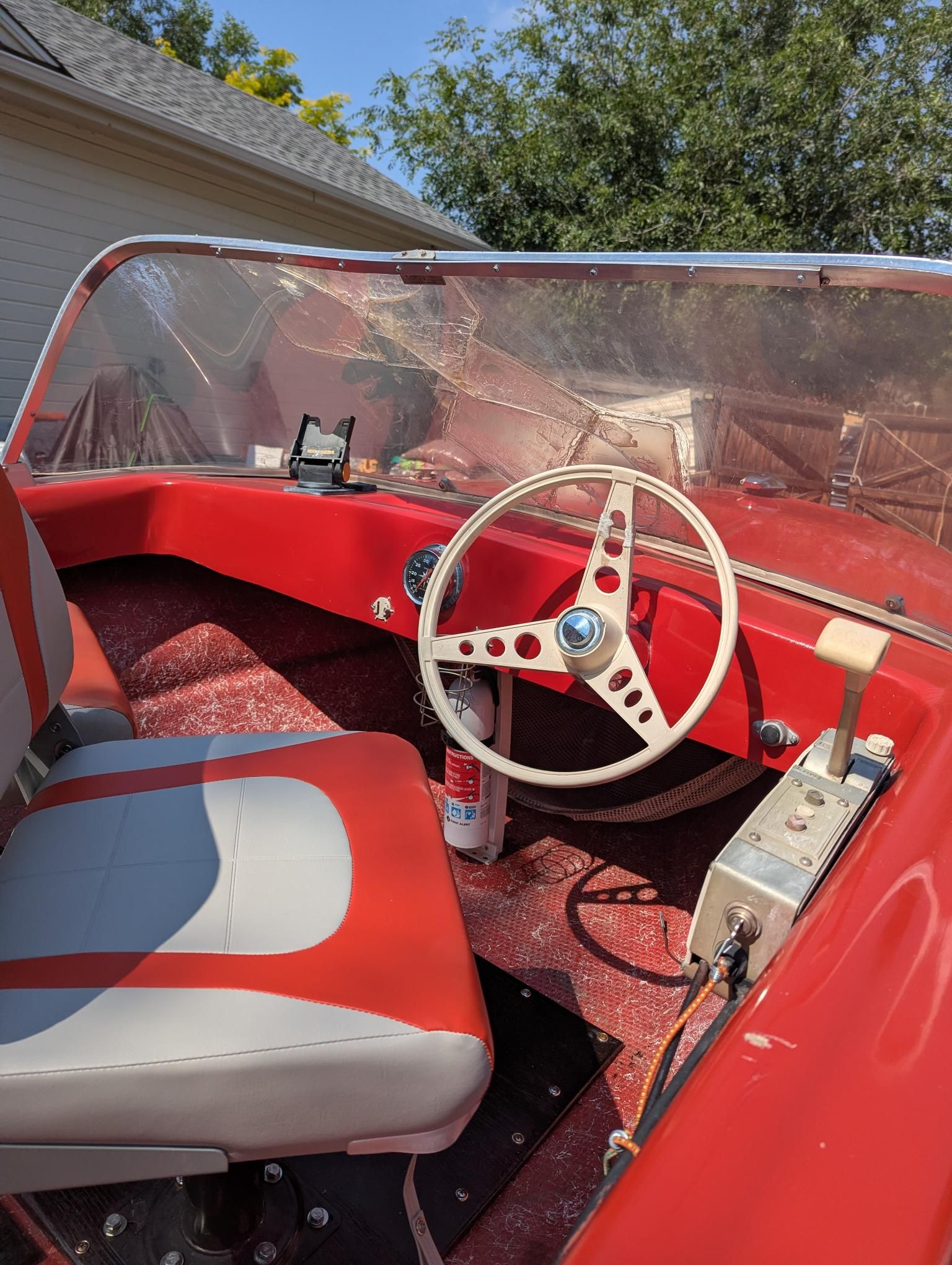 Interior view of a red 1972 14' Swiss Craft runabout with steering wheel and seat.