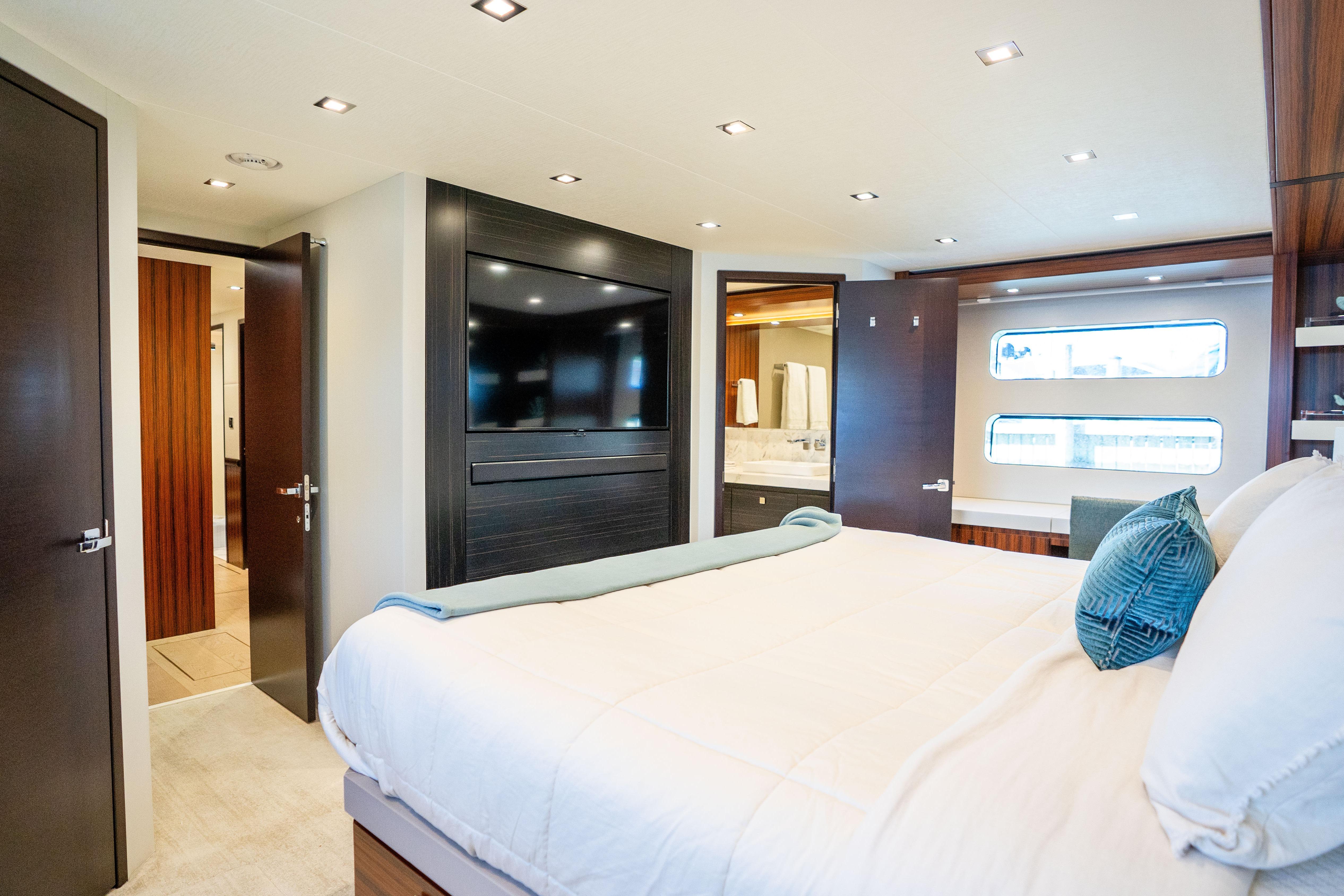 Luxurious bedroom interior of 2021 Hatteras M75 Panacera yacht with modern design and large windows.