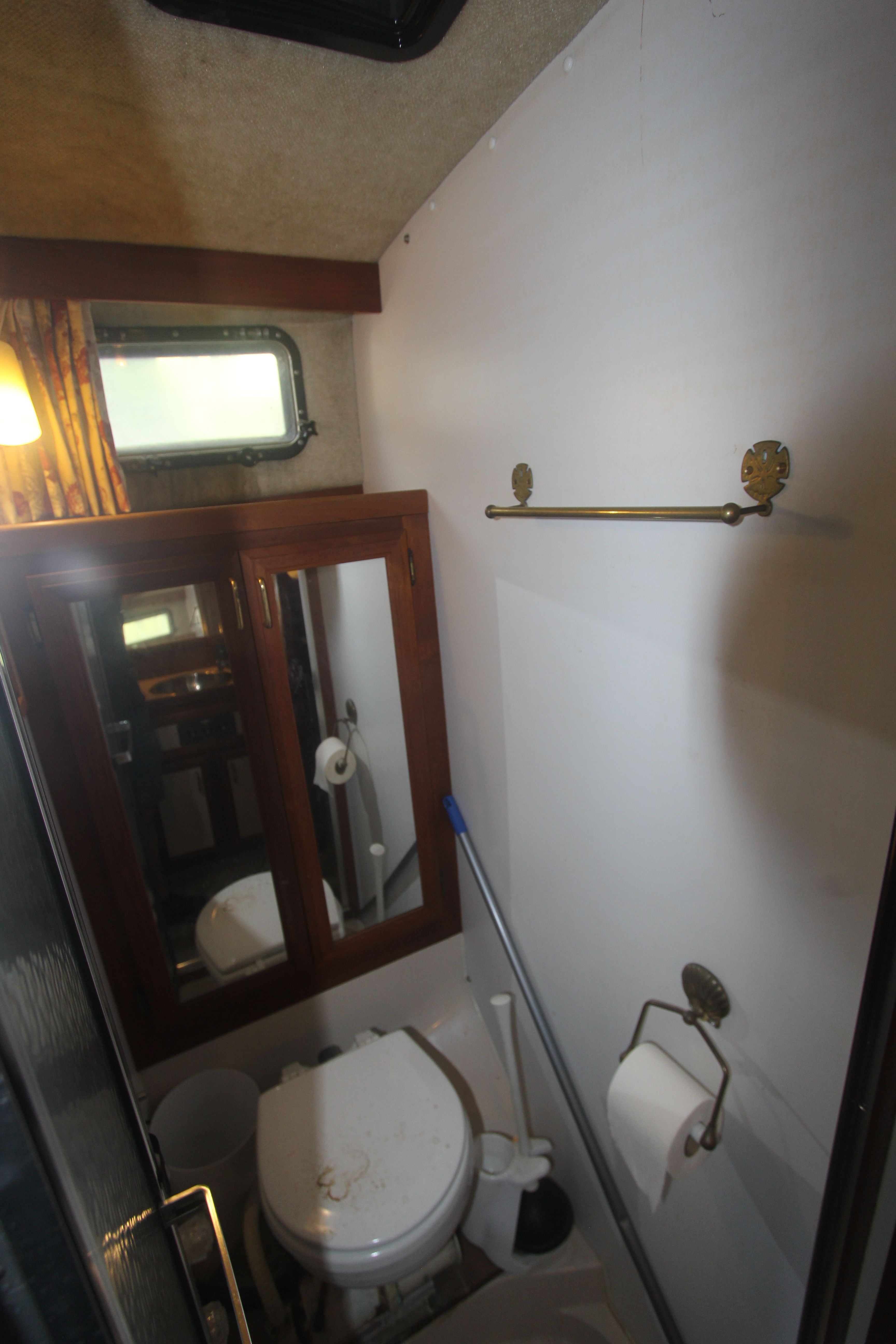 A bathroom with a toilet, mirror, and window inside a yacht.