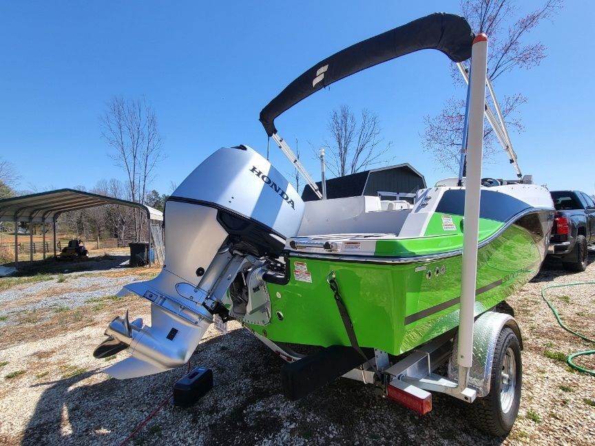 A bright green 2023 Starcraft SVX 191 OB boat on a trailer outdoors.