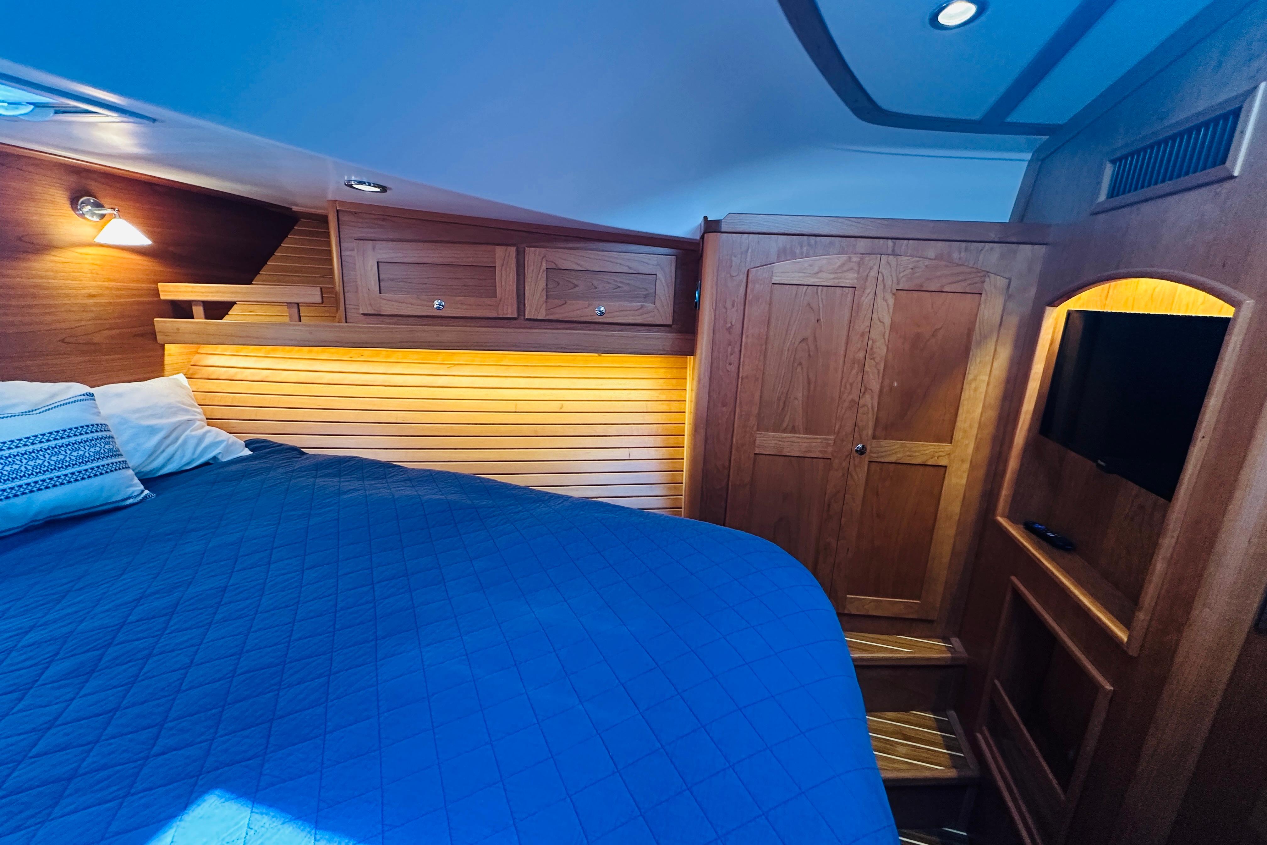 Luxurious cabin interior of 2025 Sabre 48 Salon Express with wood paneling and cozy bedding.