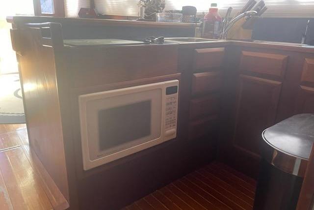 1987 Topaz 44 Flybridge kitchen with built-in microwave and wooden cabinetry.