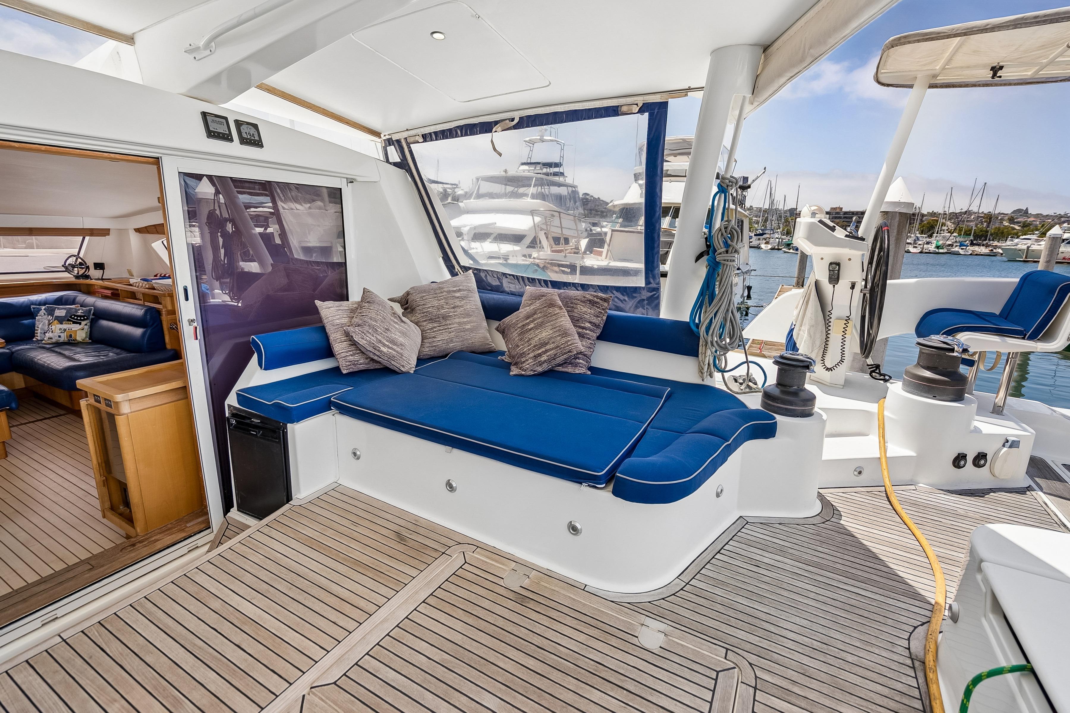 Luxurious 2009 Catana 65 yacht interior with blue seating, wooden flooring, and marina view.
