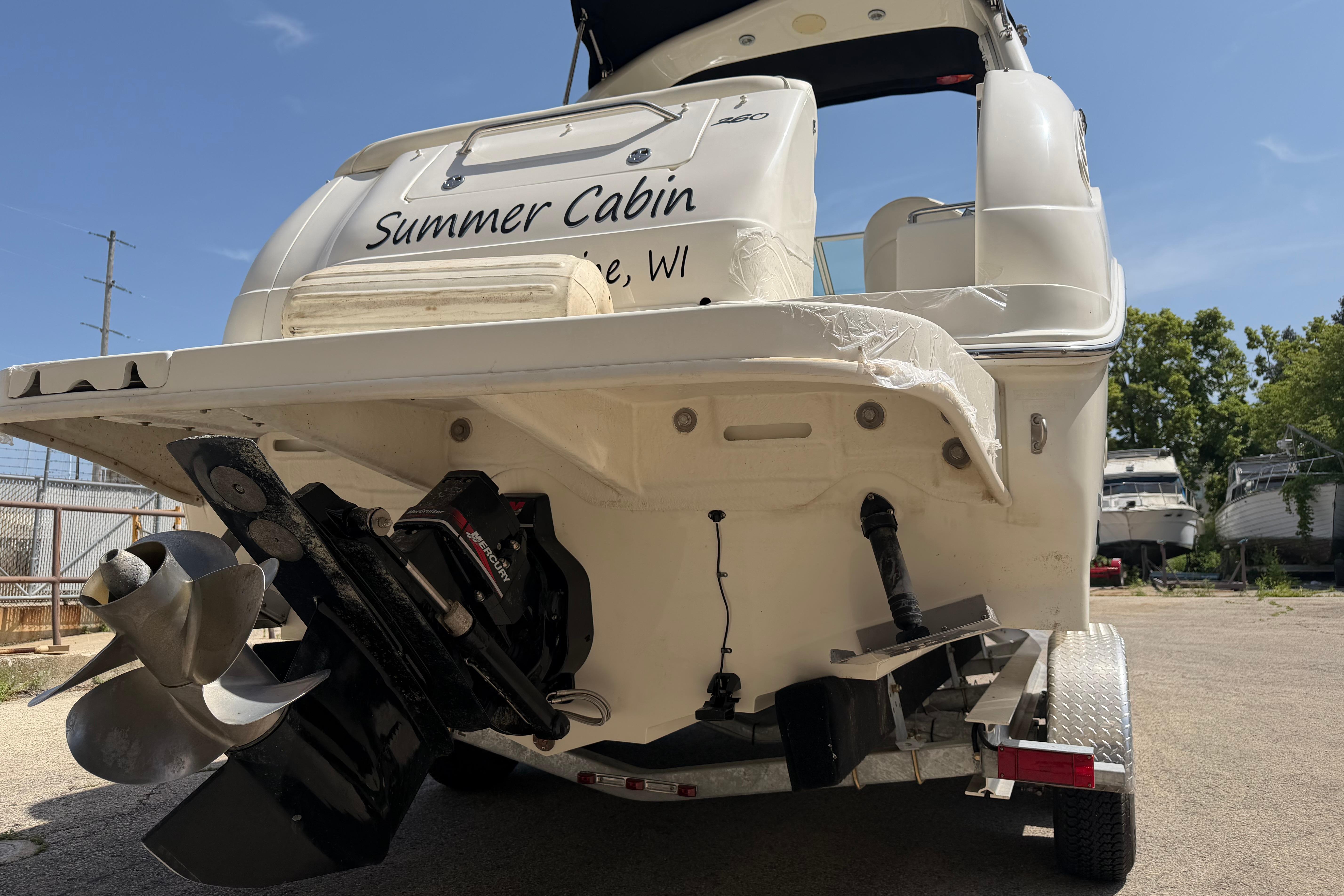 2004 Sea Ray Sundancer 260 boat on trailer, rear view with propeller and "Summer Cabin" text.