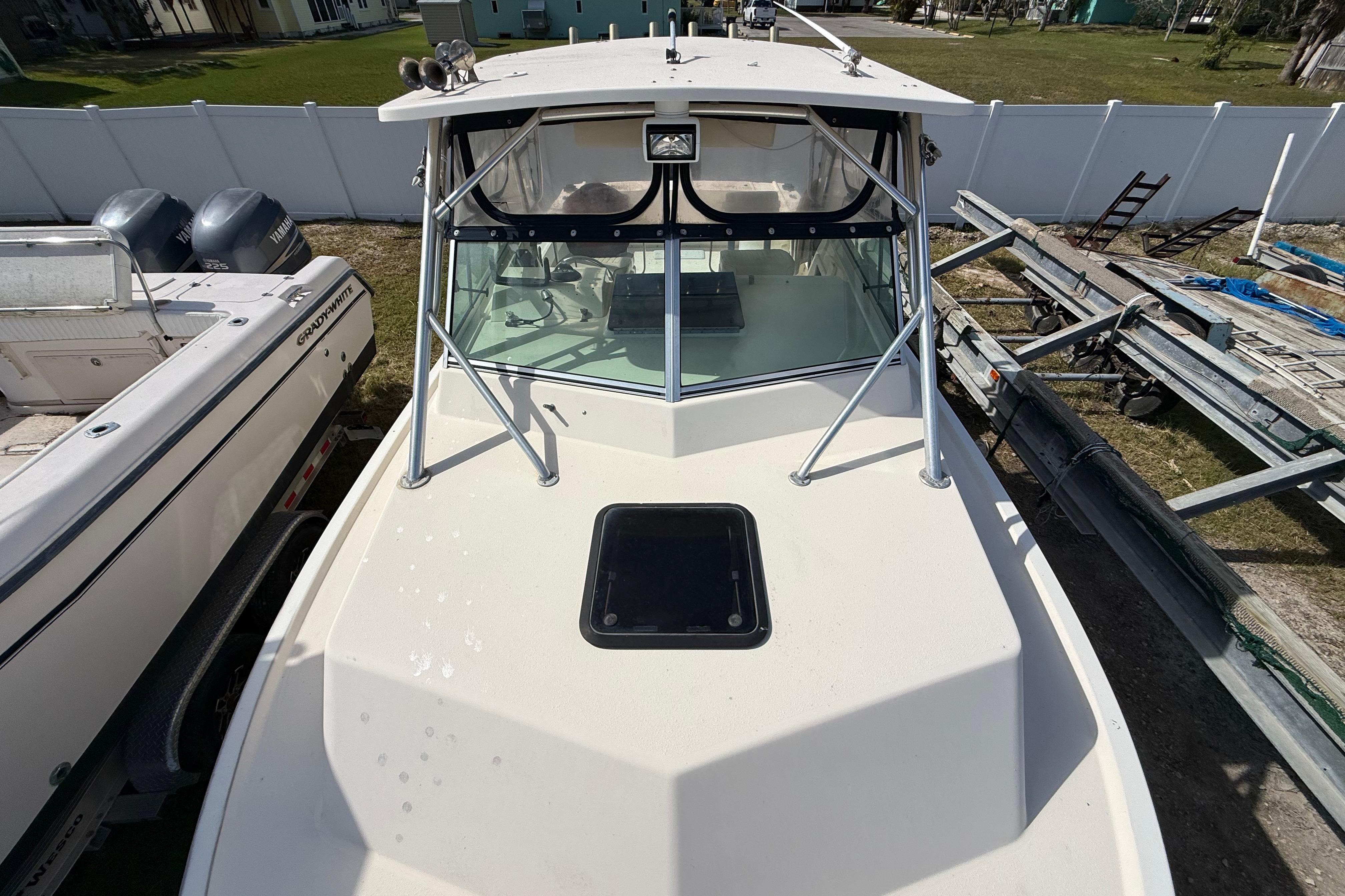 2001 Parker 2510 Walkaround boat with windshield and hatch, docked beside another vessel.