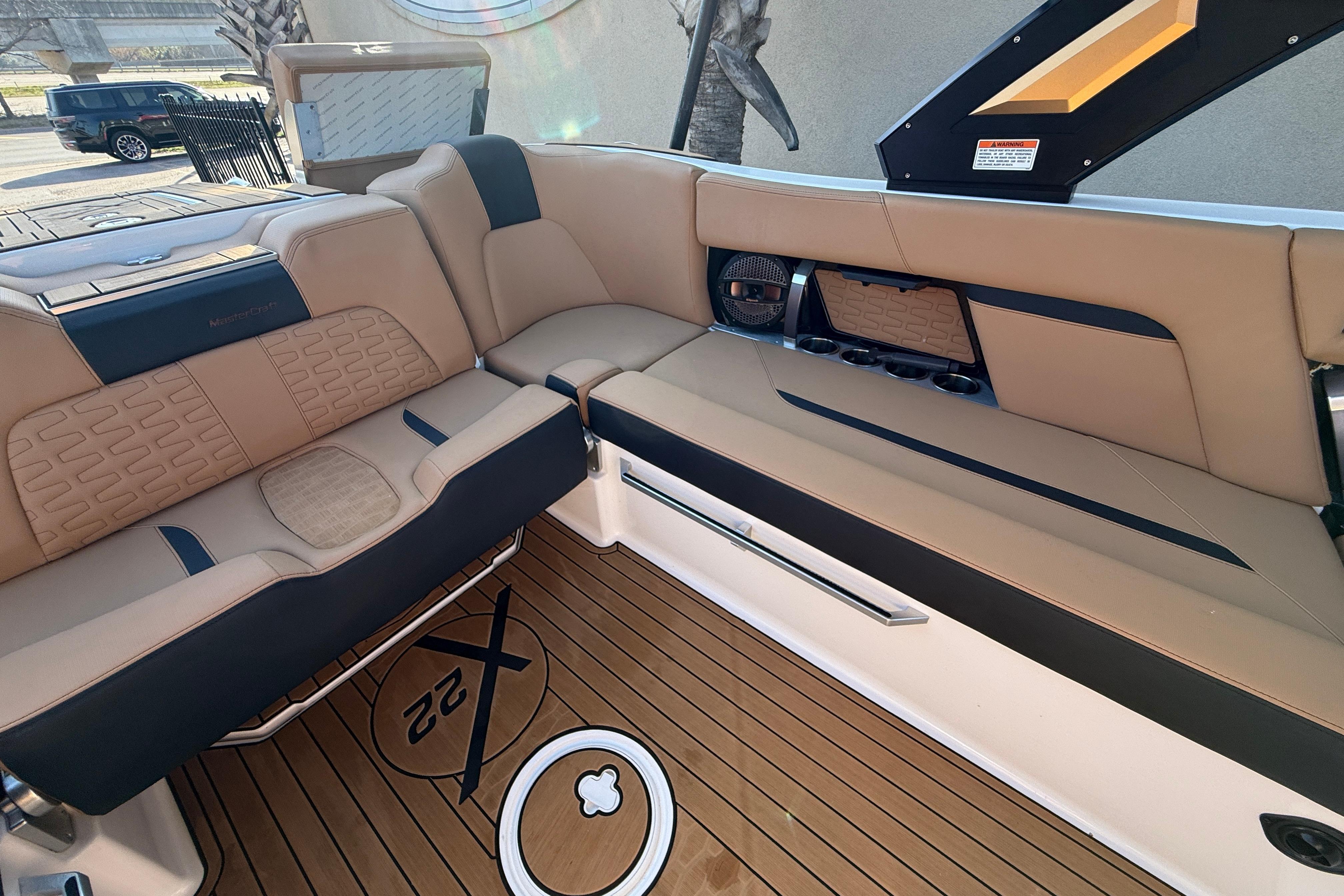 2023 MasterCraft X22 boat interior with tan and black seating, teak flooring, and cup holders.